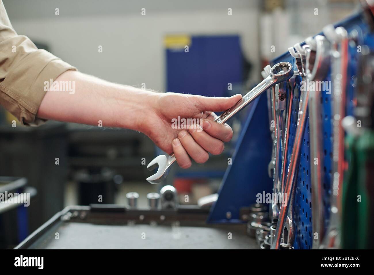 Hand des jungen Technikers, Mechanikers oder Reparaturwerkers, der eines der Schlüssel nimmt Stockfoto