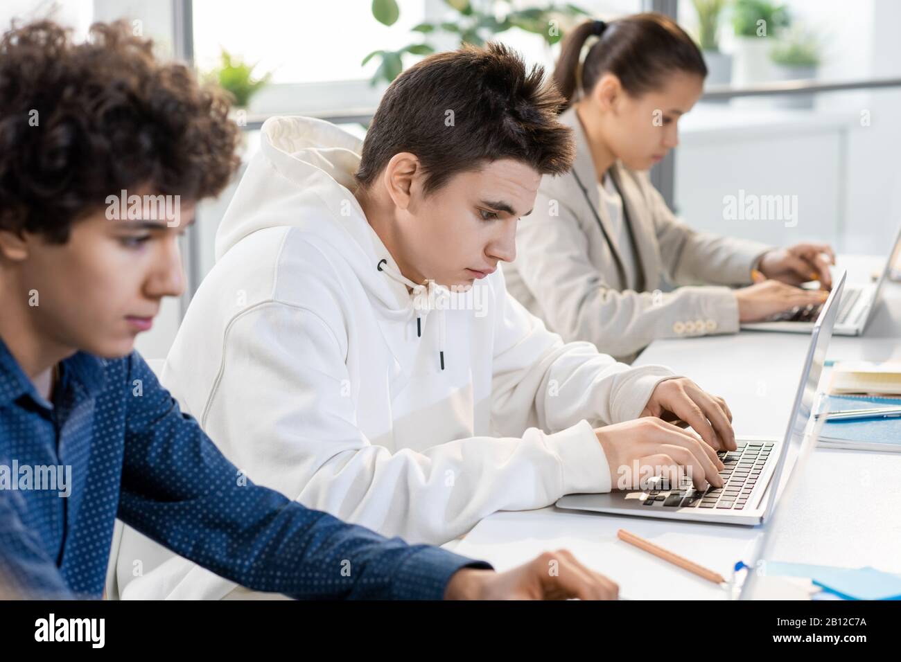 Junge ernsthafte Studenten, die während der Projektvorbereitung Daten auf dem Laptop anzeigen Stockfoto