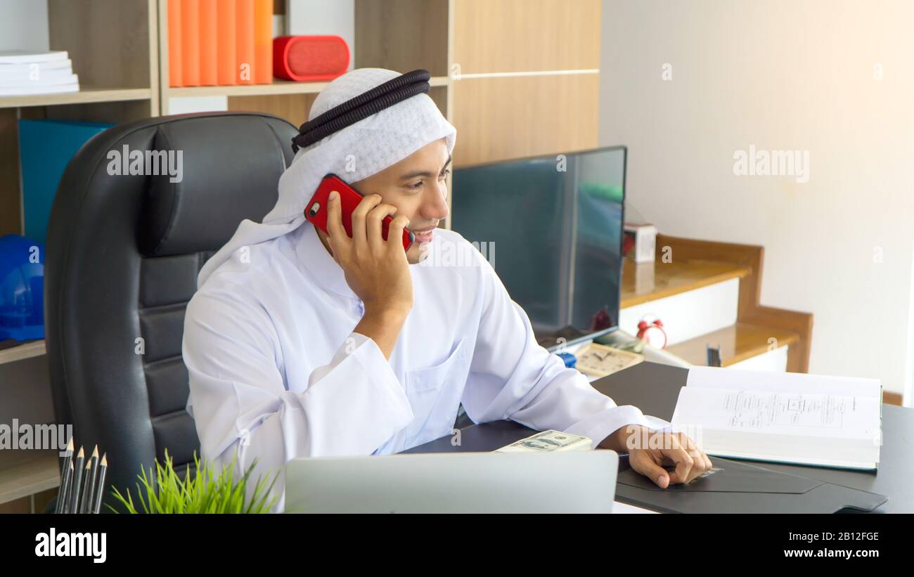 Arabische Geschäftsleute, die auf einem Laptop unterwegs sind und auf Geschäftserfolg gut gelaunt sind Stockfoto