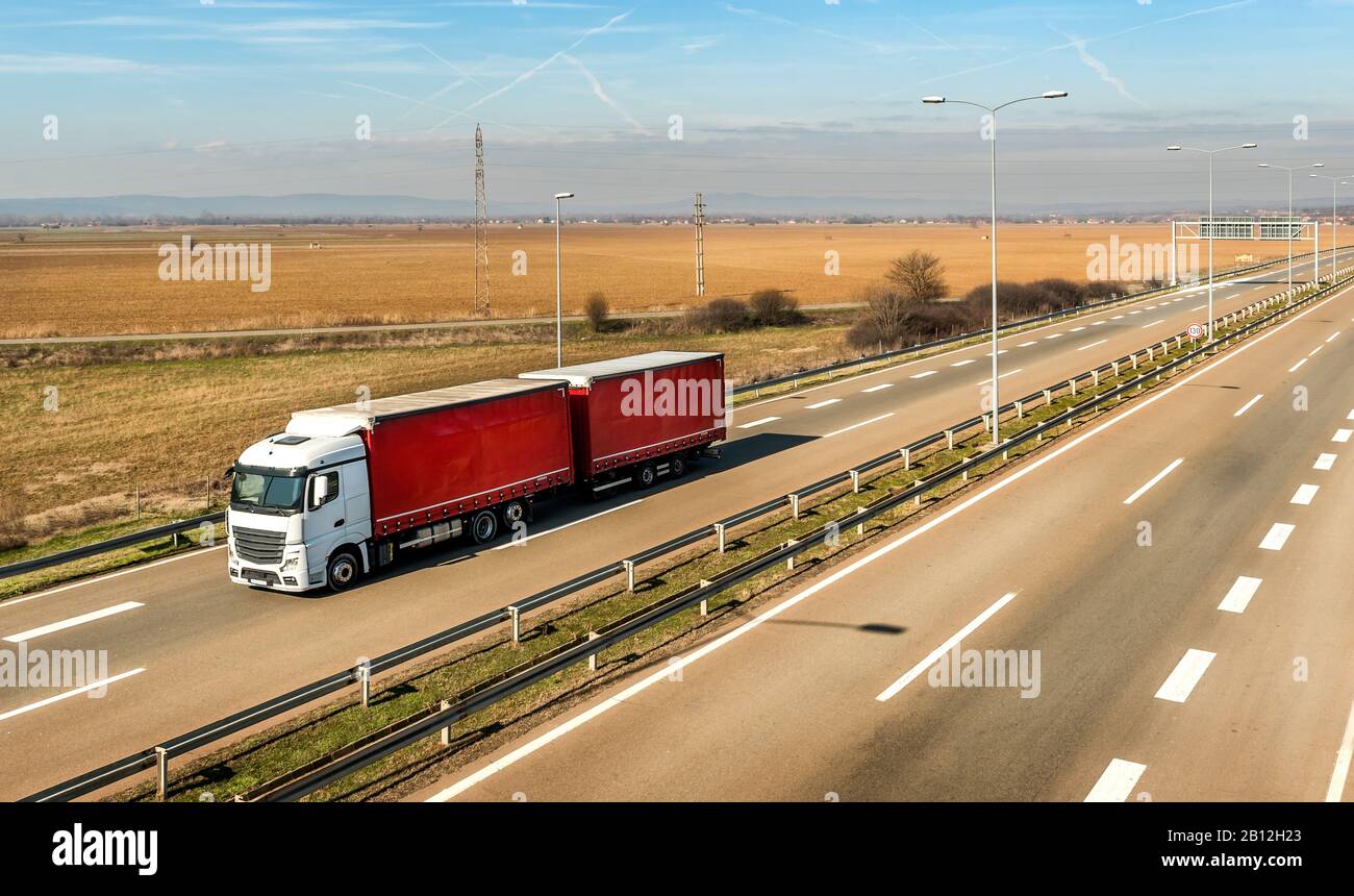 Weißer und roter Truck auf einer ländlichen Landstraße unter einem wunderschönen blauen Himmel Stockfoto