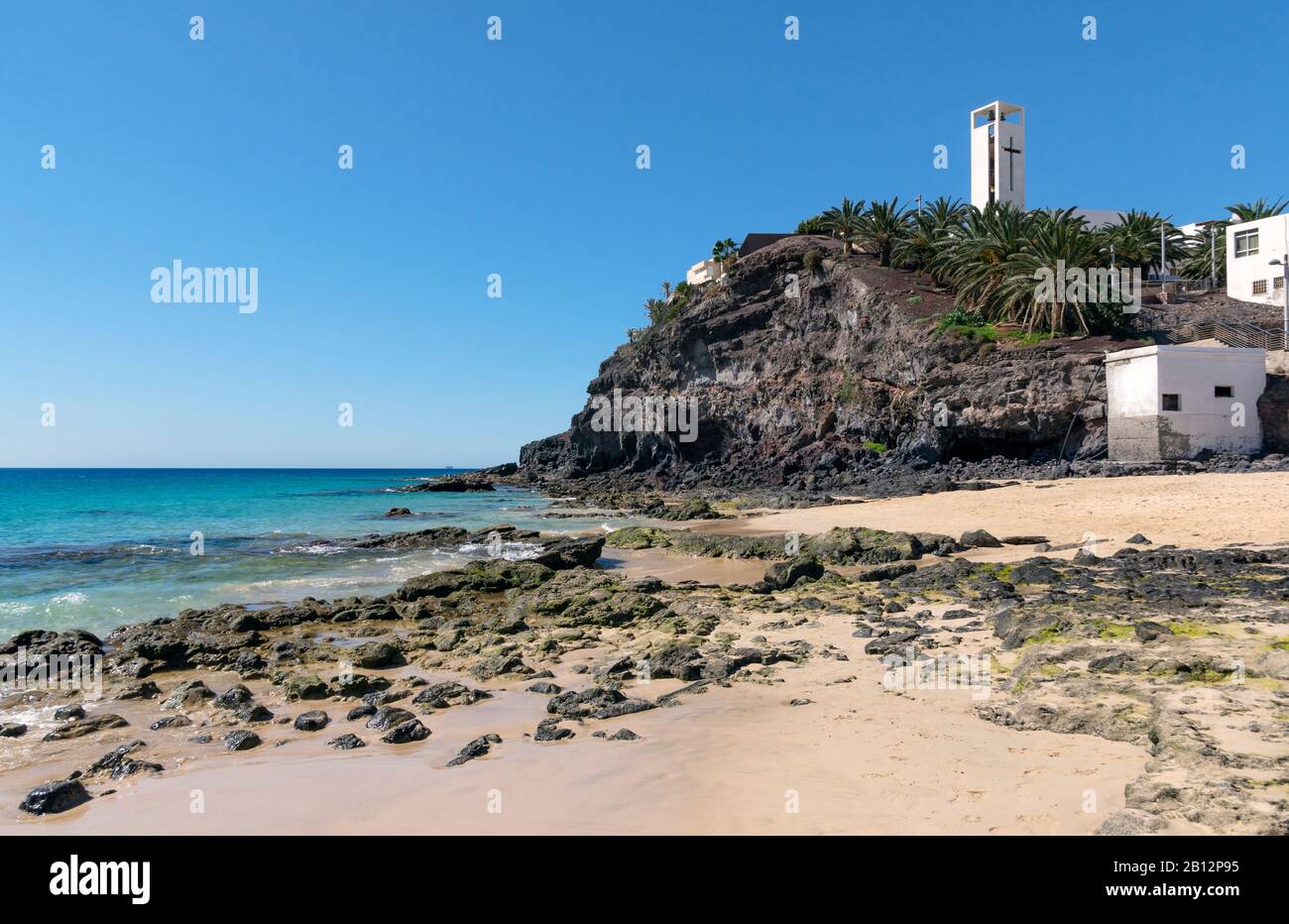 Strand in Morro Jable, der zur Kirche am Felsen führt Stockfoto