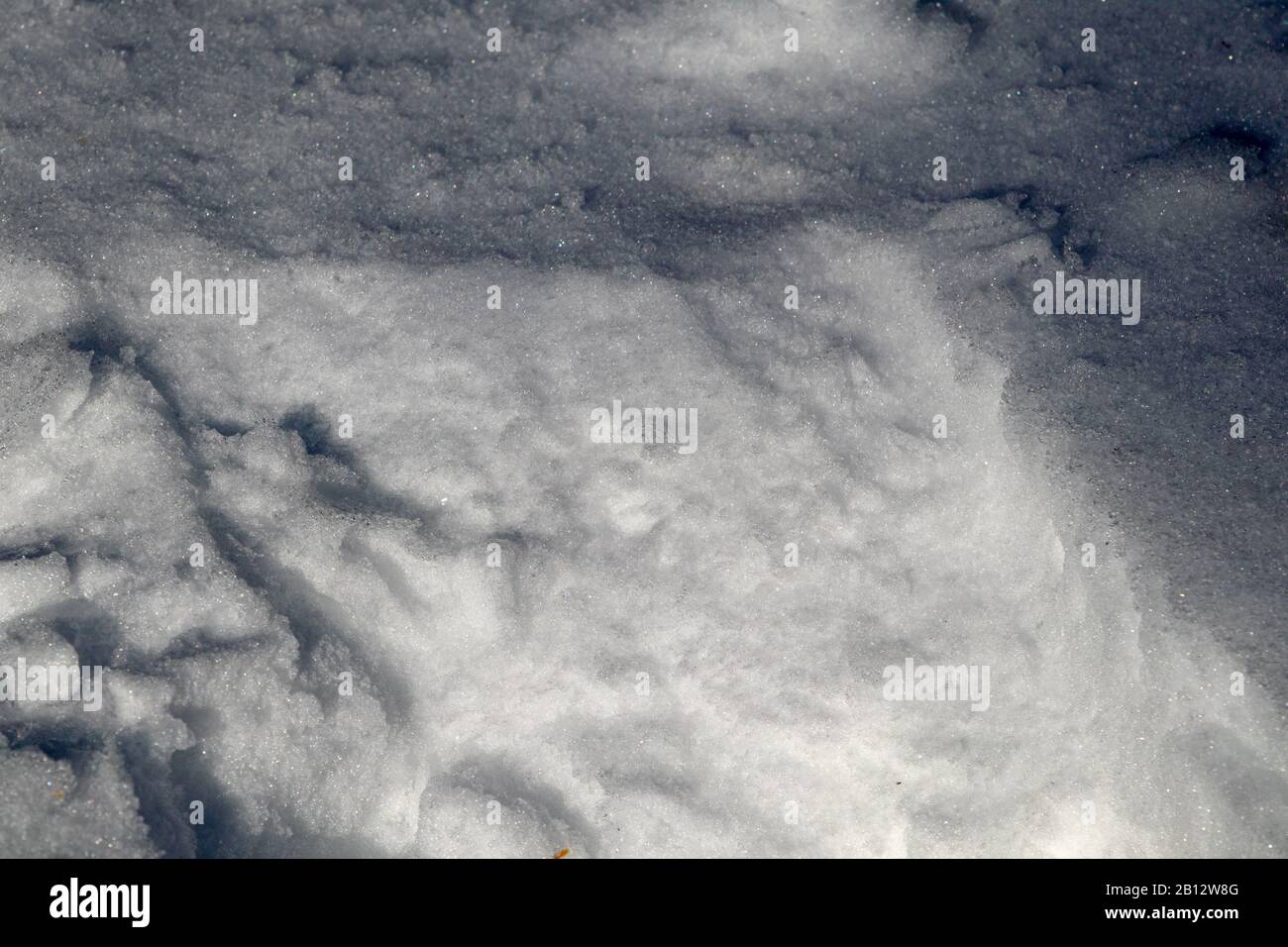 Die Oberfläche von tiefem Schnee auf dem Boden ist nah zu sehen und zeigt die Details seiner Beschaffenheit im Winter. Der natürliche Schnee wurde auf einer Seite gestört. Stockfoto