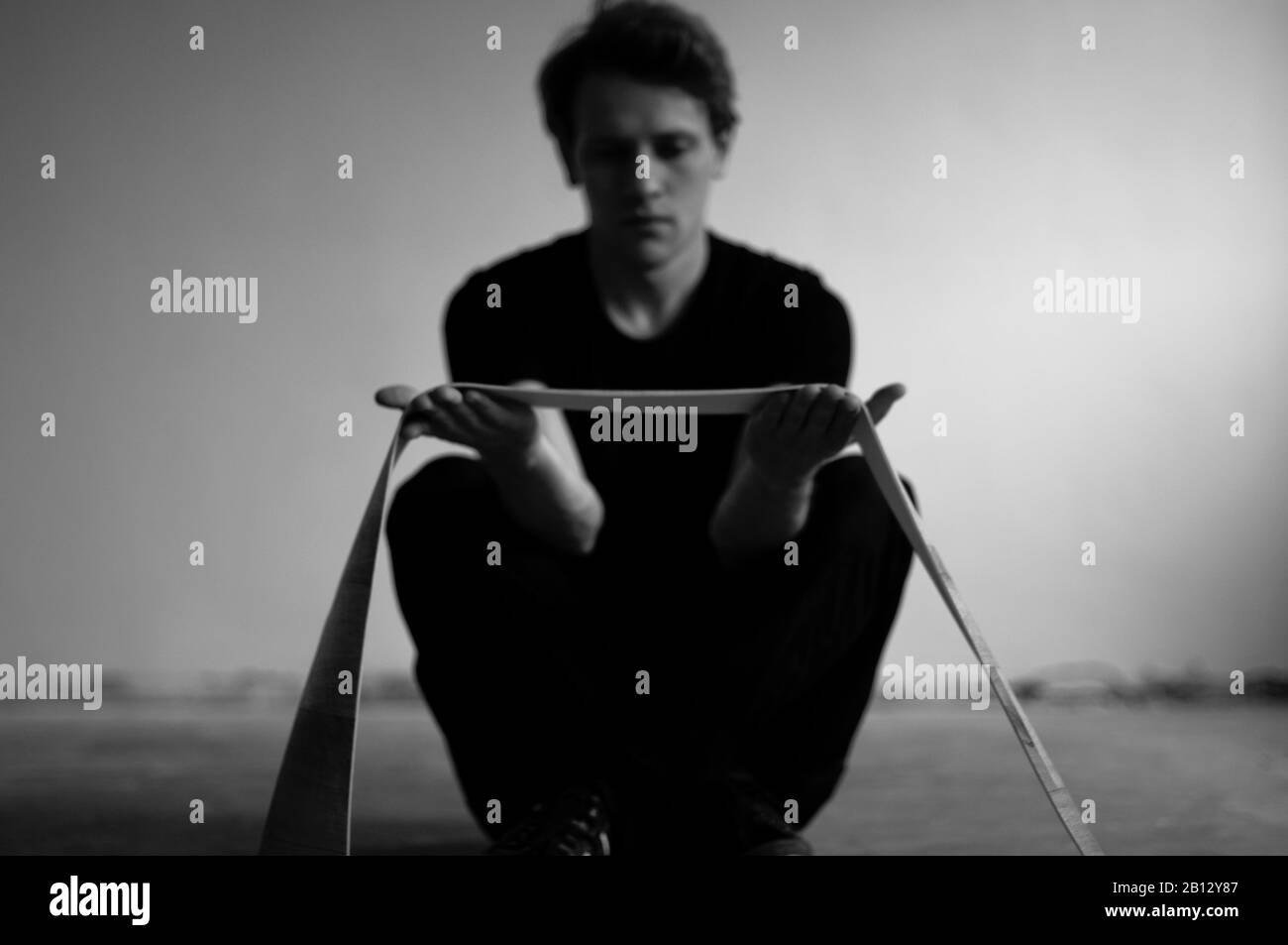 Junger Mann auf dem Boden sitzend Stockfoto