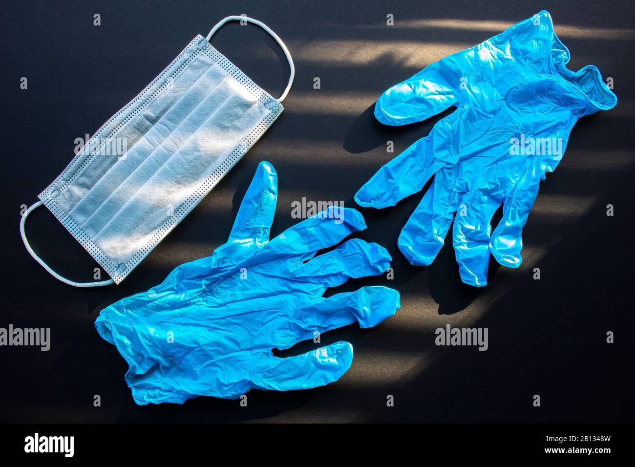 Chirurgische Masken, Einweg- und medizinische Handschuhe Mit Gesichtsmaske auf schwarzem Hintergrund Stockfoto
