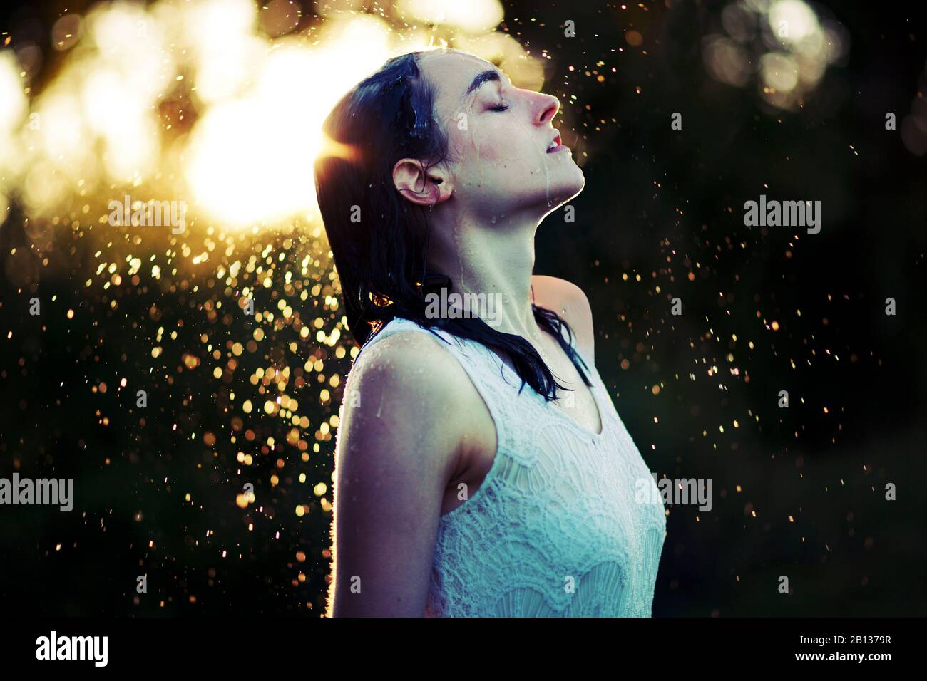 Junge Frau, die sich im regen erfrischend Stockfoto