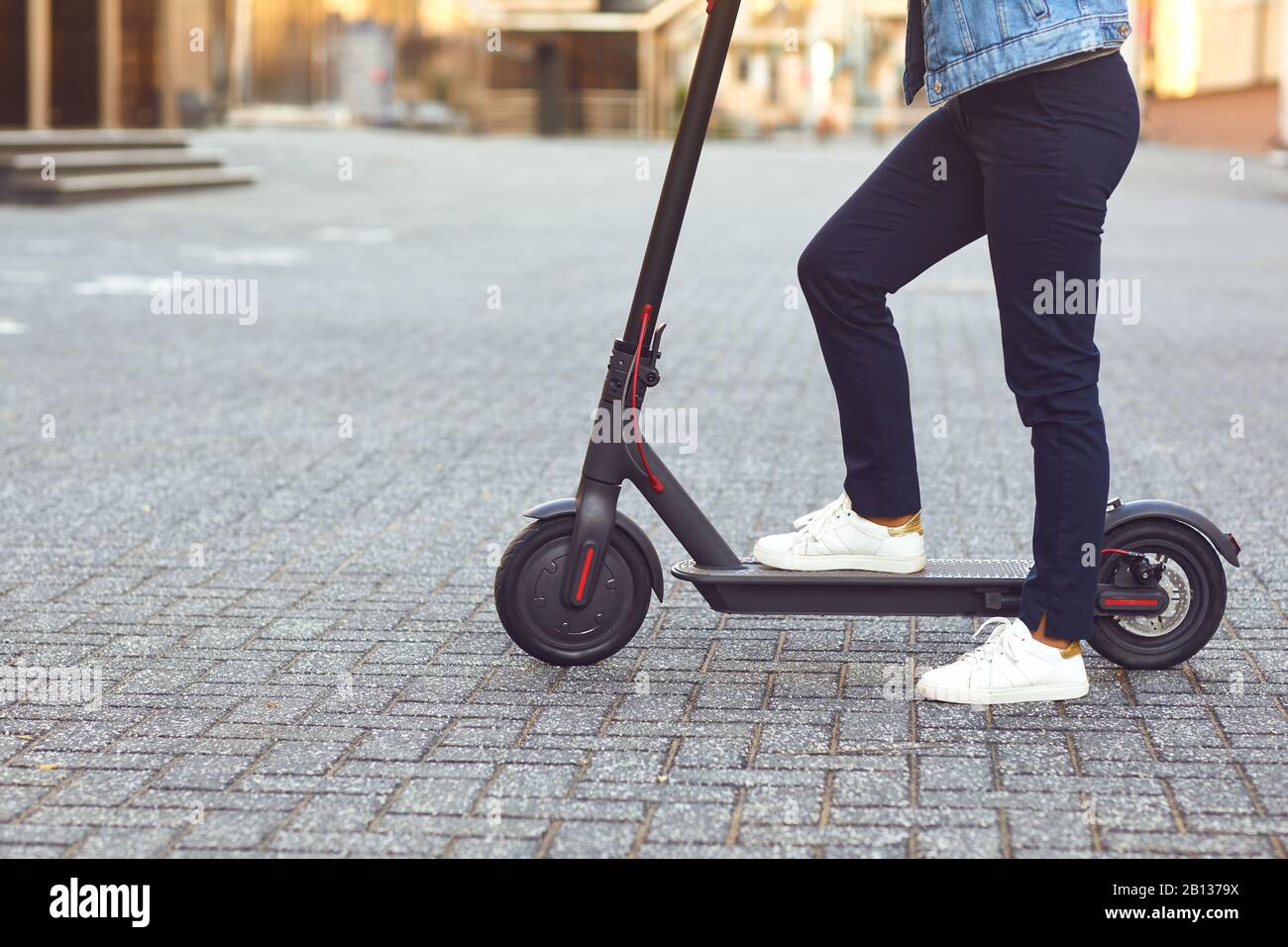 Junger Mann in einem Helm reitet einen Elektroroller auf einer Straße der Stadt im Sommer Stockfoto