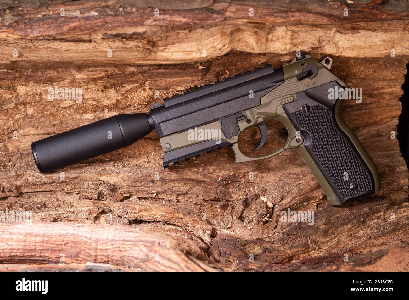 Khaki-Pistole mit Schalldämpfer. Gewehr auf Holzhintergrund. Stockfoto
