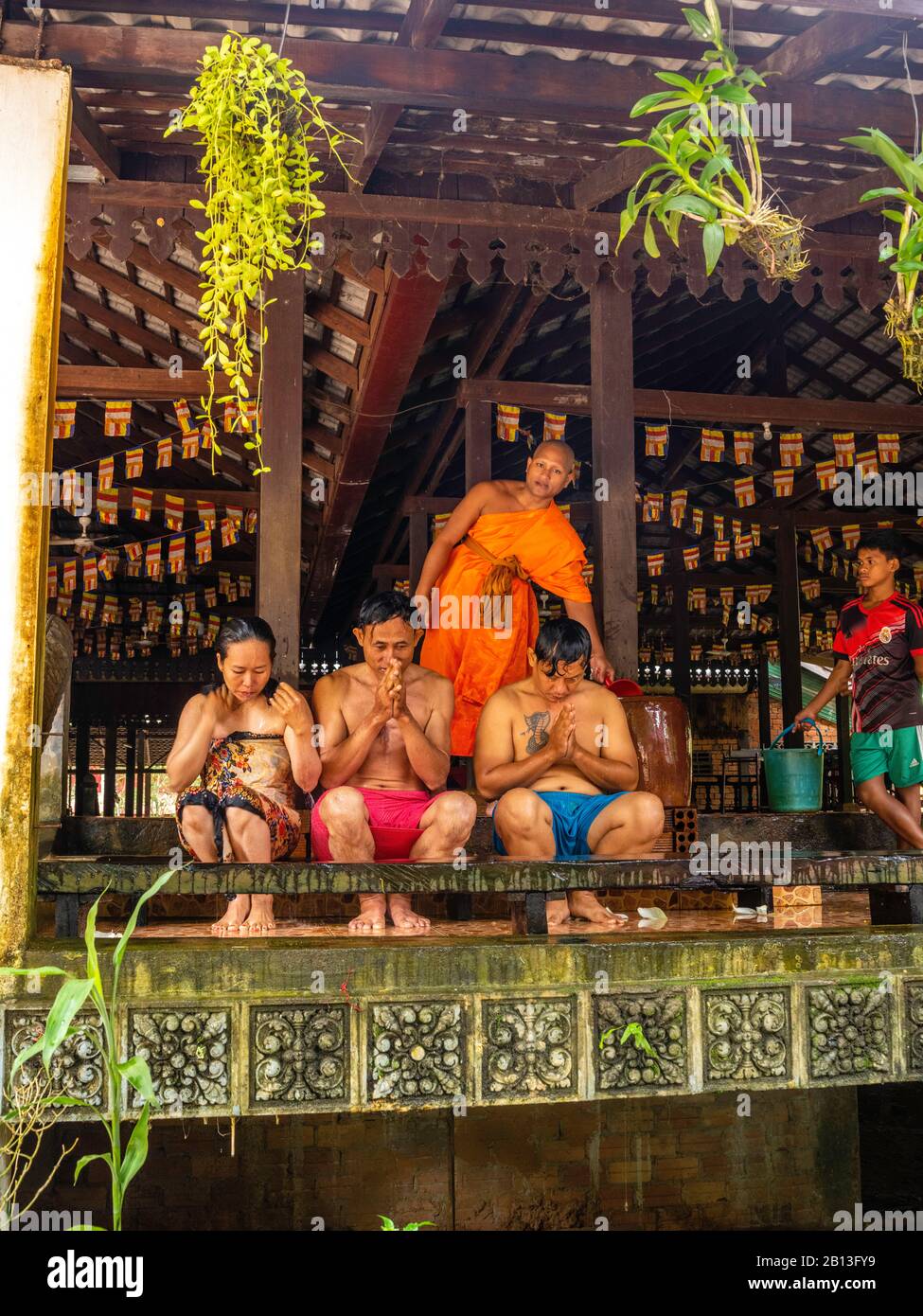 Drei Menschen erhalten während des Wasserfestes einen Wassersegnung von einem Mönch in einem buddhistischen Tempel in Kambodscha. Angkor Wat Archäologischer Park, Siem Reap, C. Stockfoto