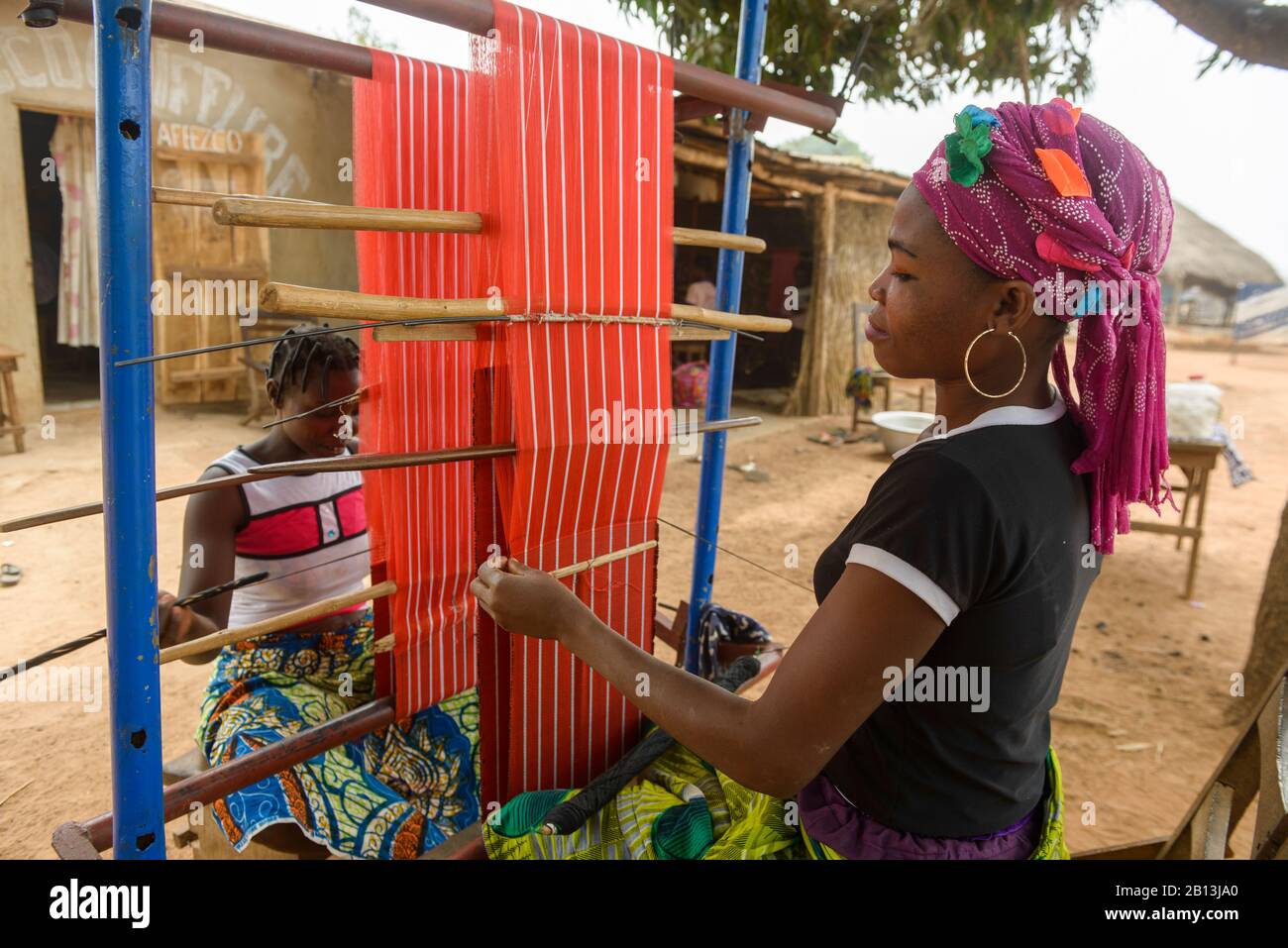 Mädchen und Frauen, die an ihren Webstühlen in einem Dorf im Norden Benins, Afrika arbeiten Stockfoto