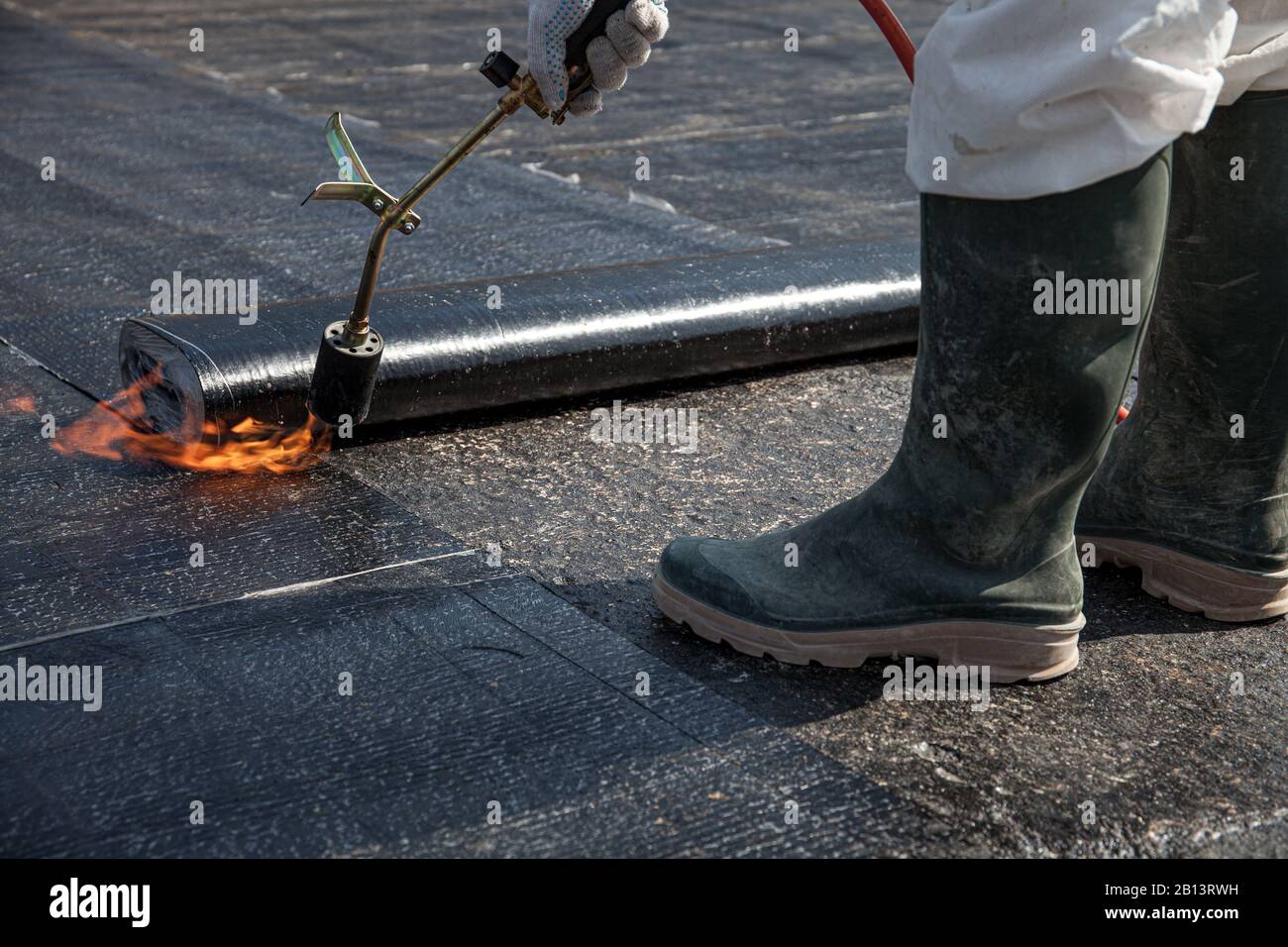 Arbeiter überlagern das Dachmaterial auf der flachen Betonoberfläche Stockfoto