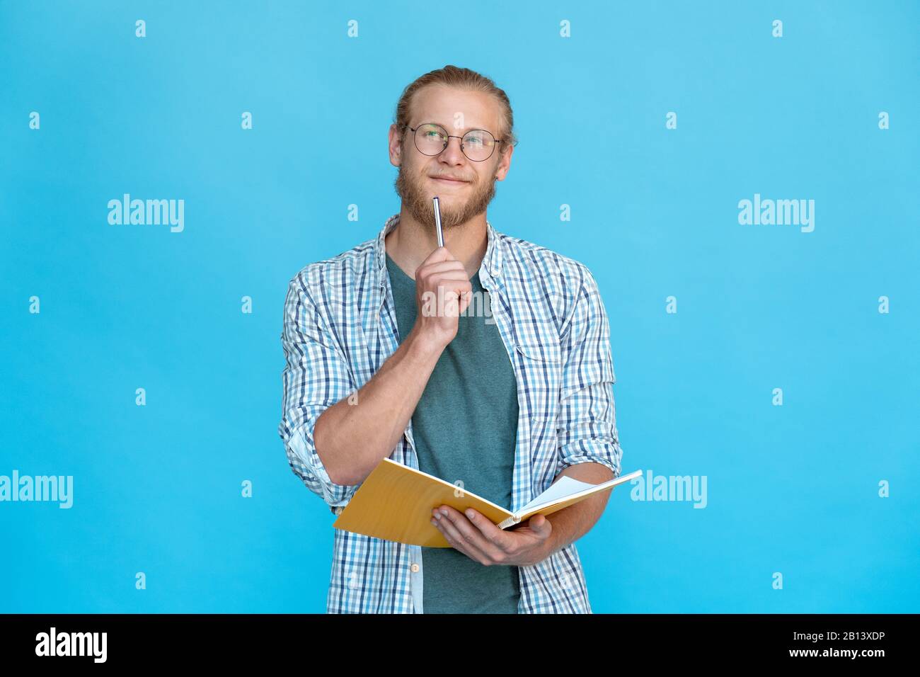 Junger nachdenklicher träumerischer Mann hält Stift am Mund, denkt, Plan macht Notizen Tagebuch Stockfoto