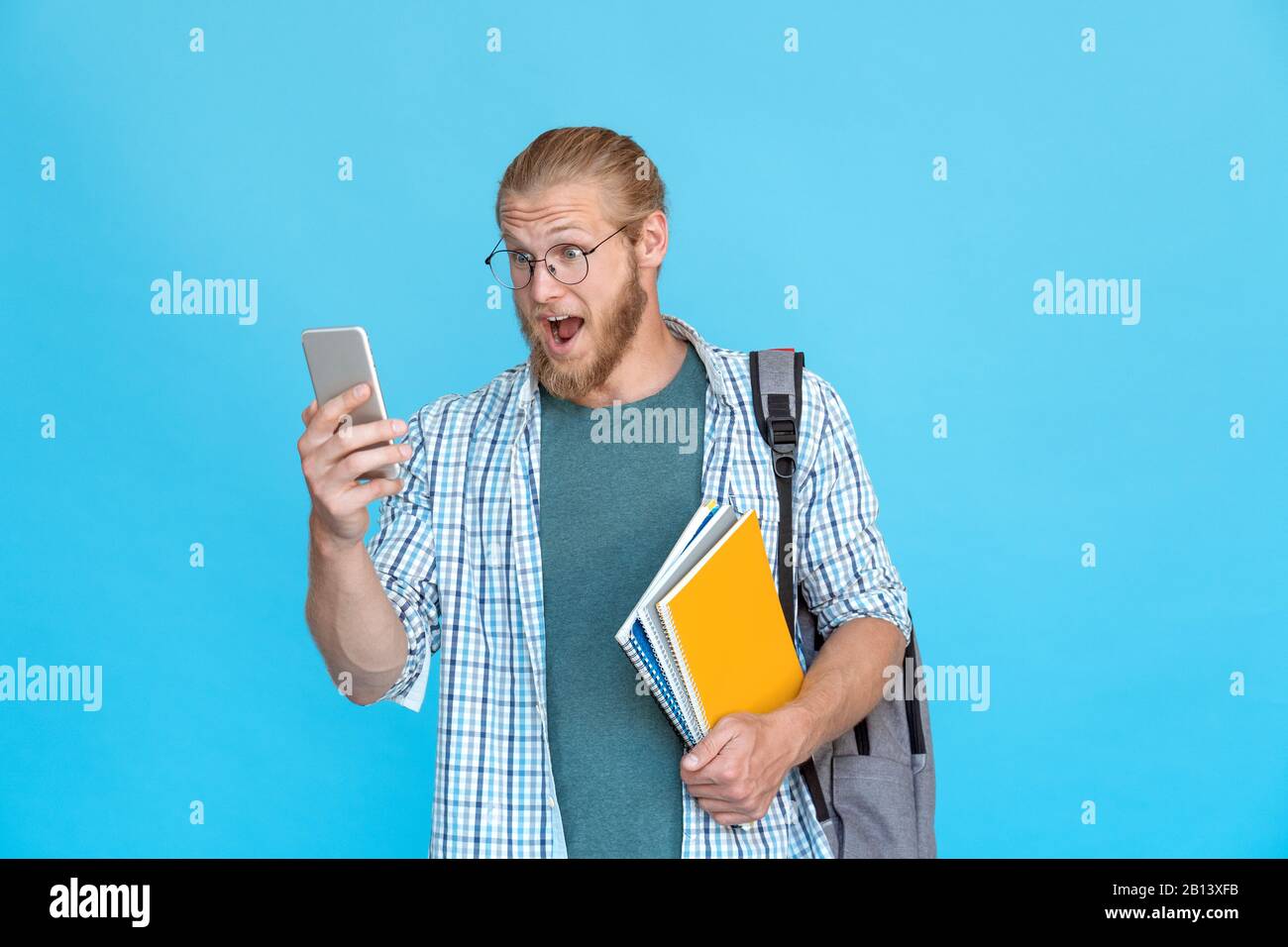 Bärtige Studentenbrille weckt Emotionen halten modernes Smartphone Textnachricht lesen Stockfoto