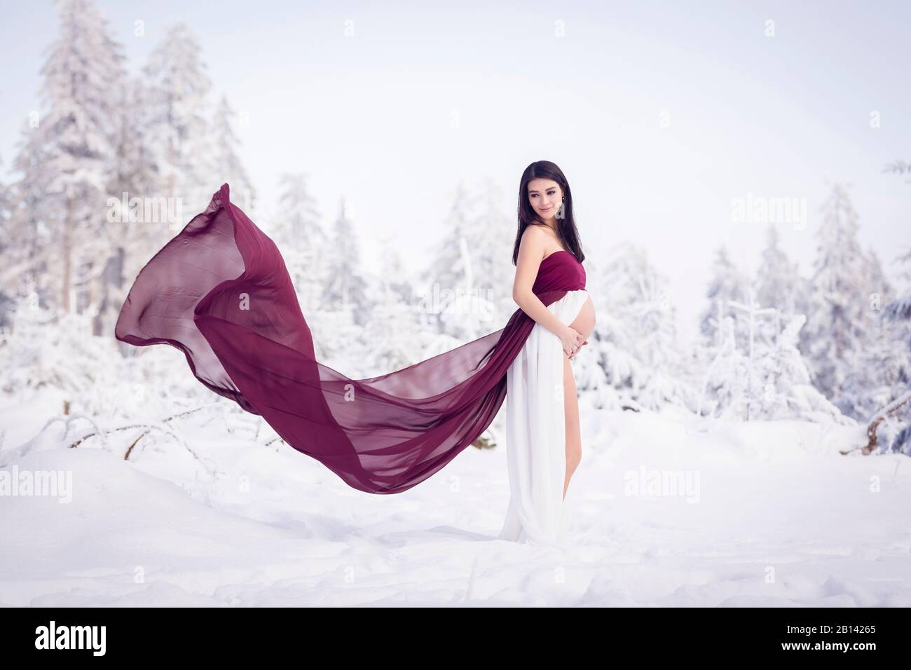 Schwangere Frau steht im Schnee Stockfoto