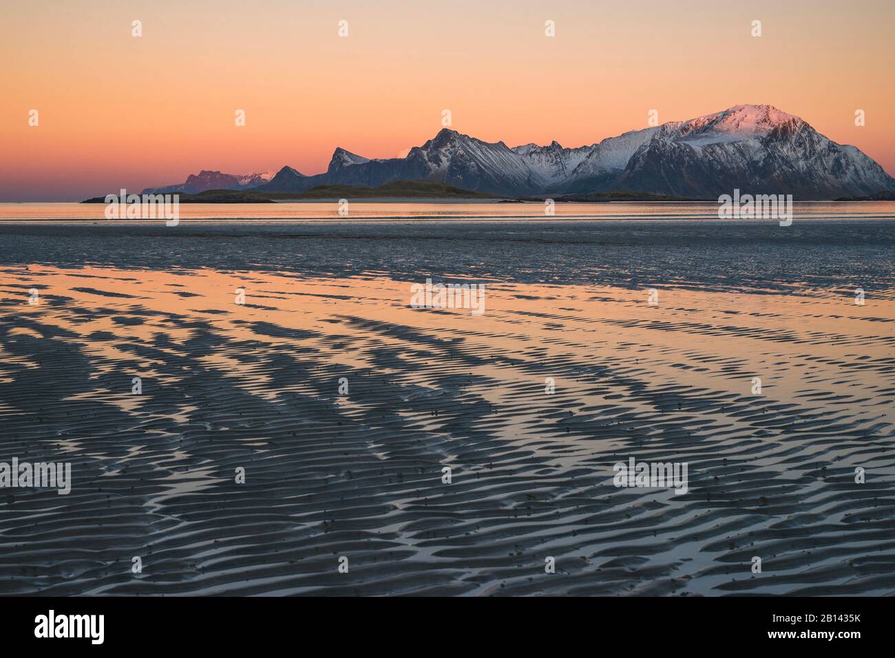 Zarte Farben des Sonnenuntergangs sind in den Pfützen auf dem Strand bei Ebbe, Lofoten, Nordland, Norwegen Stockfoto