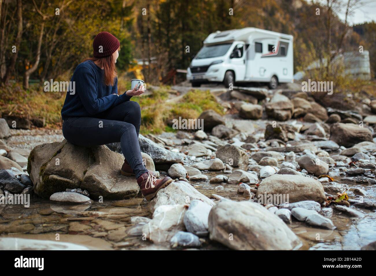 Road Trip l Frau sitzt mit einer Tasse Tee vor dem Wohnmobil Stockfoto