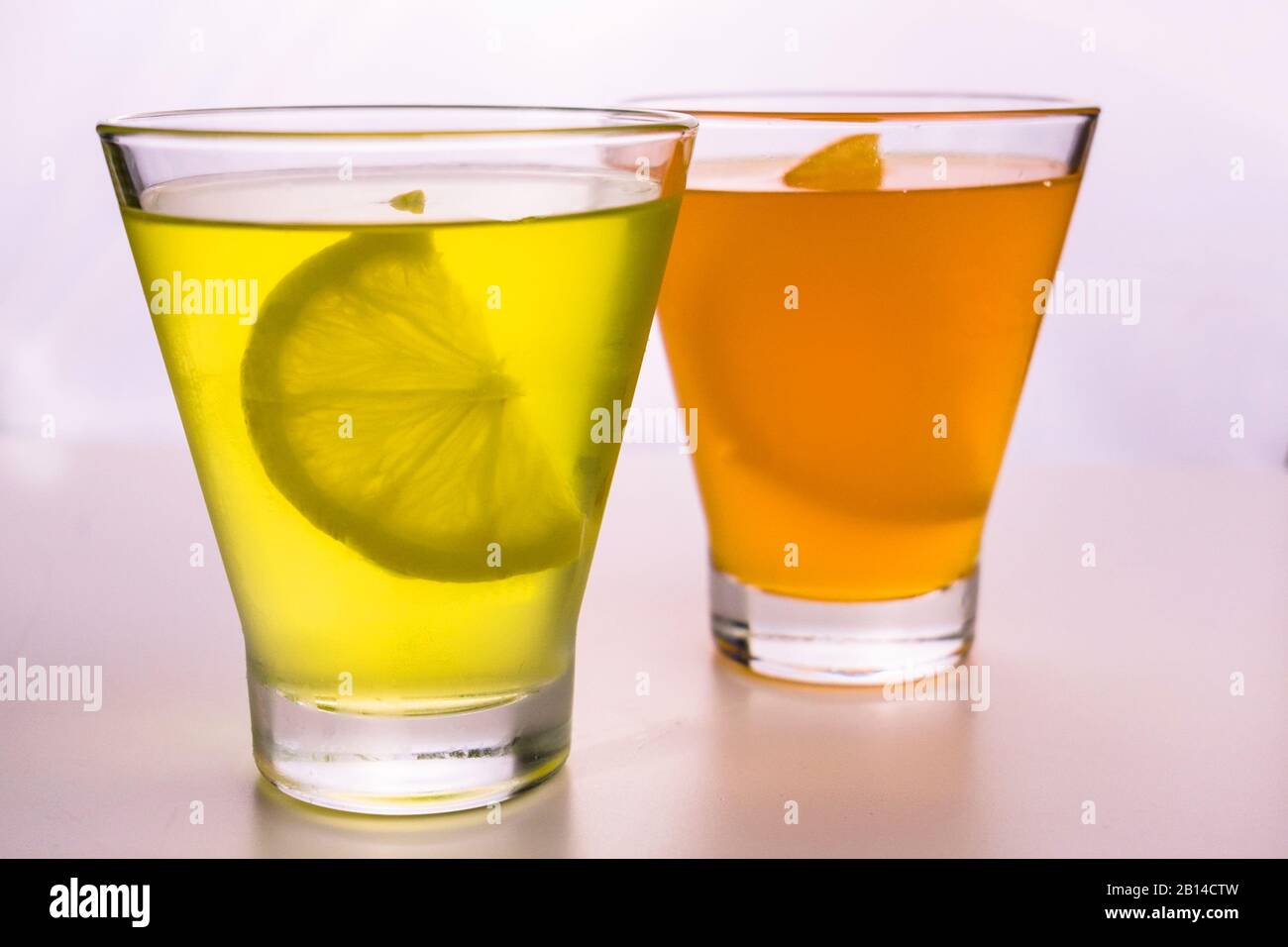 Zitronengelb und orangefarbenes Gelee in Gläsern auf weißem Hintergrund. Stockfoto