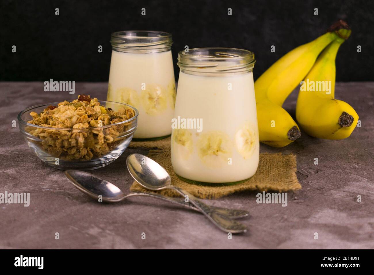 Weiches Dessert aus Bananenjoghurt und Granola auf dunklem Hintergrund. Nützliche Desserts. Stockfoto