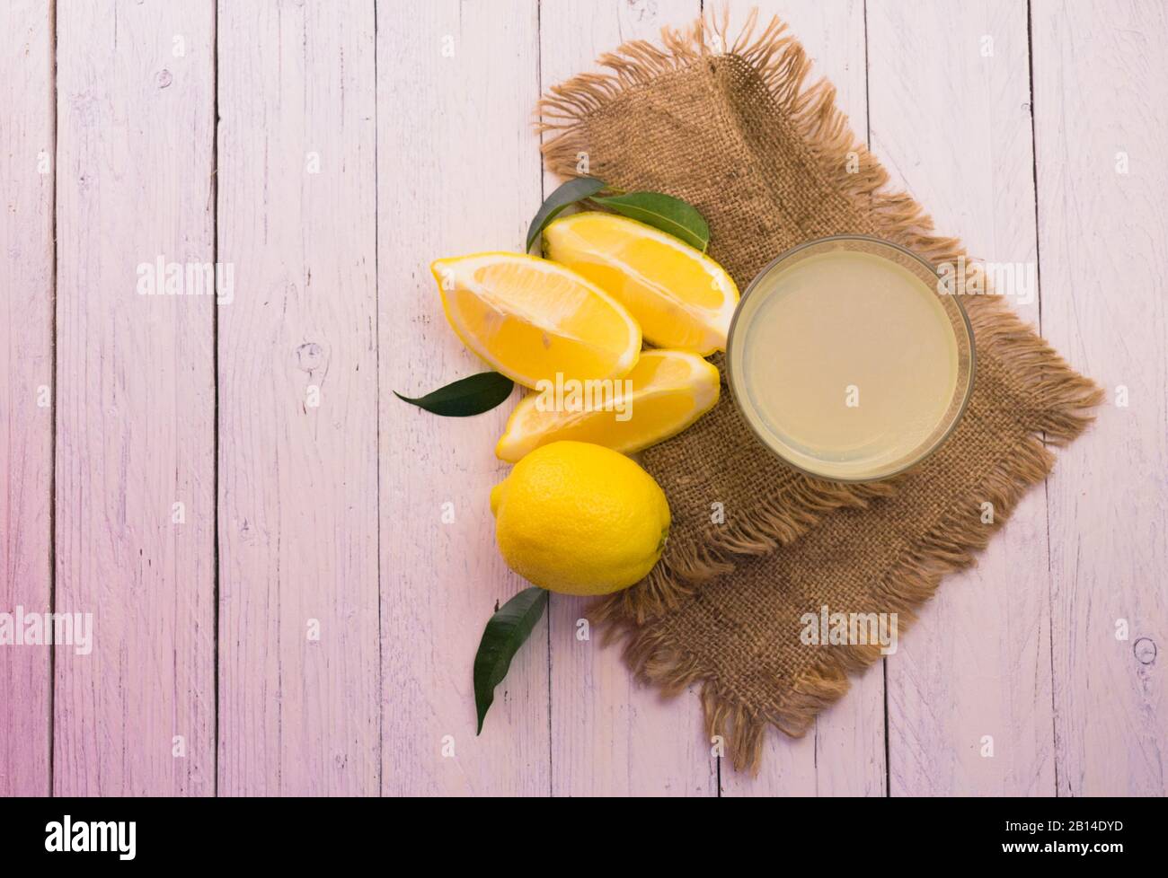 Gasse mit frisch gepresstem Zitronensaft auf weißem Holzhintergrund. Draufsicht. Kopierbereich. Stockfoto