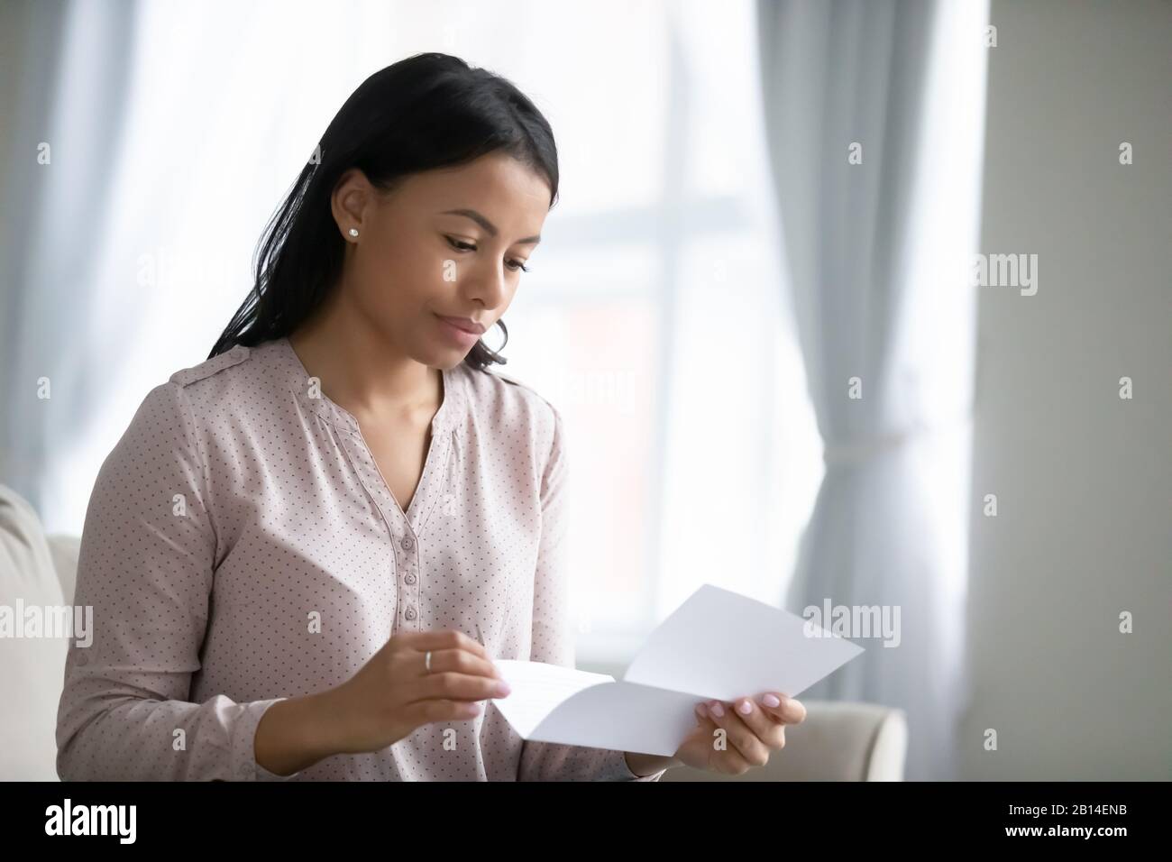Nachdenkliche biraziale Frau liest Briefpost zu Hause Stockfoto