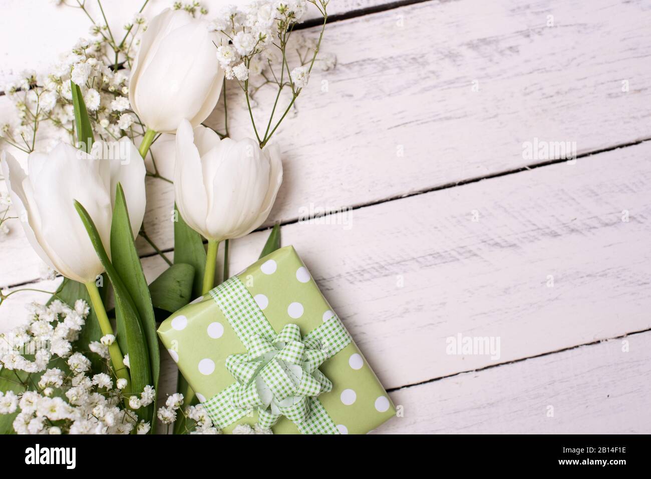 Frühlings-Tulpenblumen, Geschenkbox und Papierkarte auf grauem Steintisch von oben in flacher Laienform. Begrüßung für Frauen oder Mütter Stockfoto