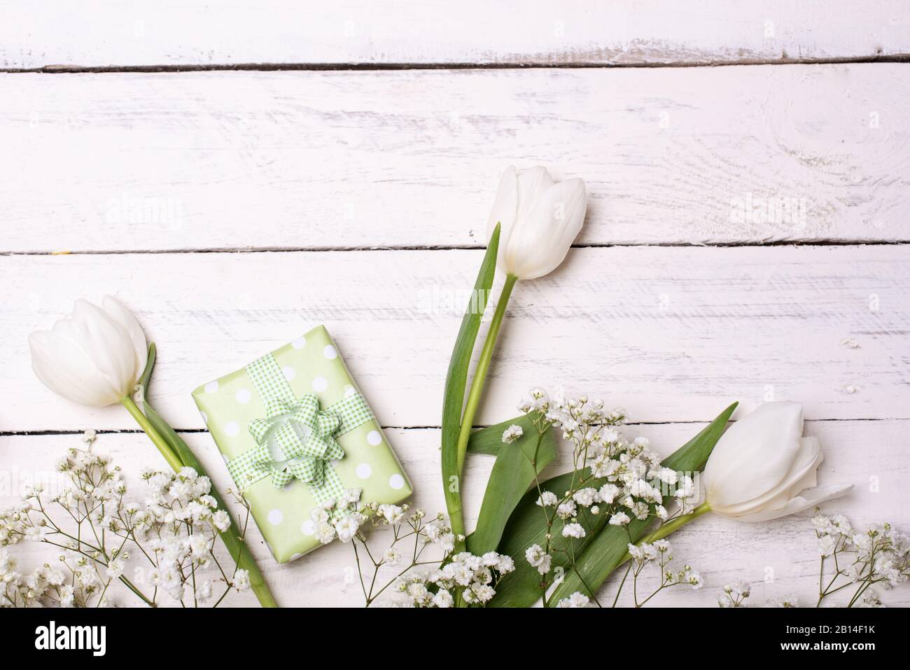 Frühlings-Tulpenblumen, Geschenkbox und Papierkarte auf grauem Steintisch von oben in flacher Laienform. Begrüßung für Frauen oder Mütter Stockfoto