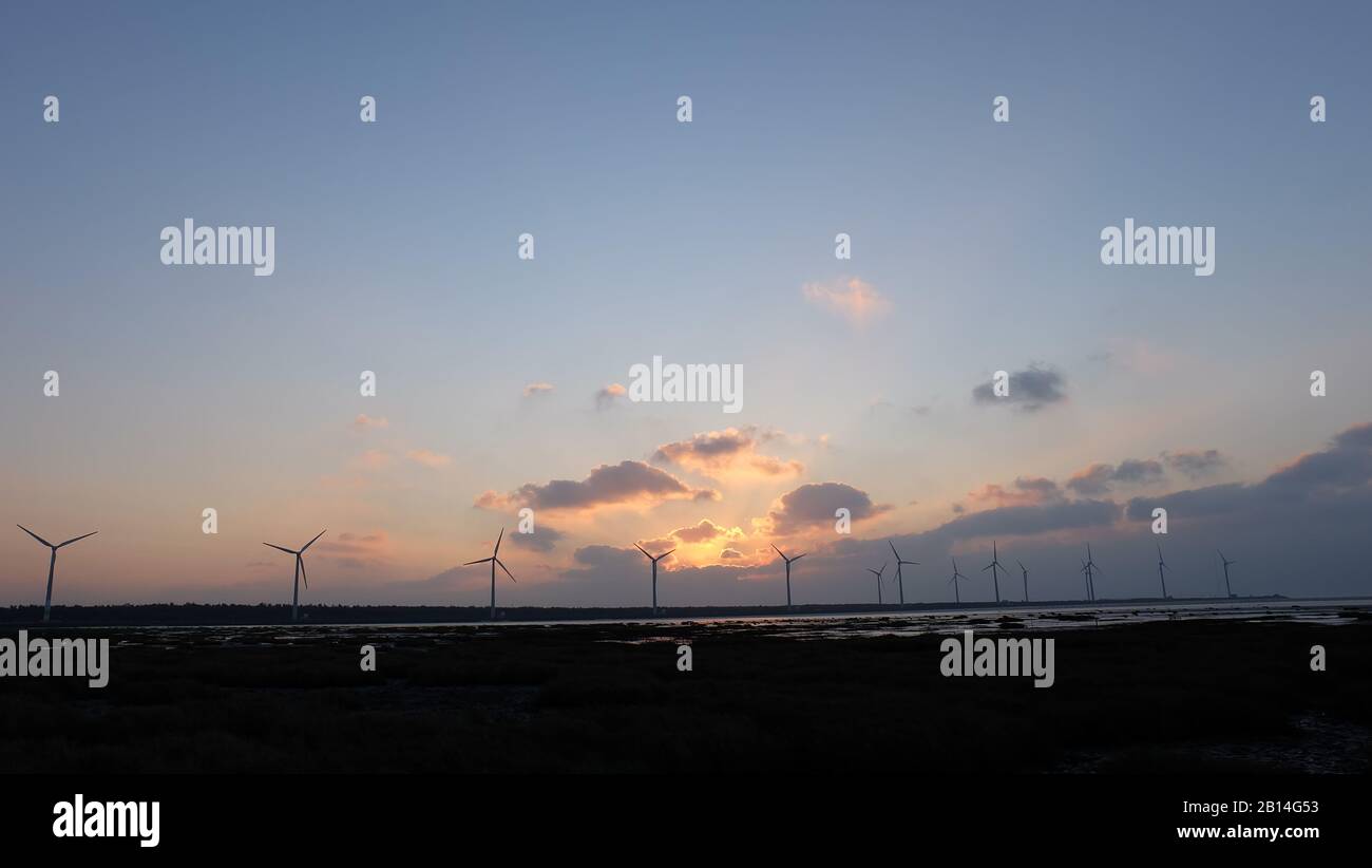 Sonne untergeht am Abend, mit Silhouette von Windkraftanlagen im fernen Horizont. Stockfoto