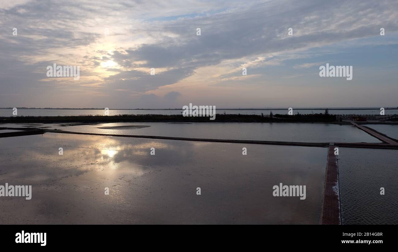 Wasser überschwemmtes Feld mit dem Spiegelbild des Abendhimmels mit untersetzter Sonne. Stockfoto