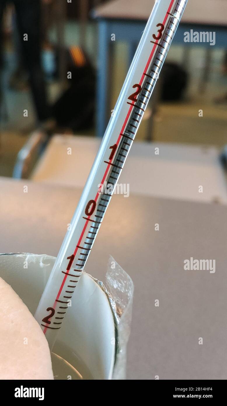 Klassisches Thermometer in einer Tasse Wasser, das für Experimente in der wissenschaftlichen Klasse verwendet wird Stockfoto