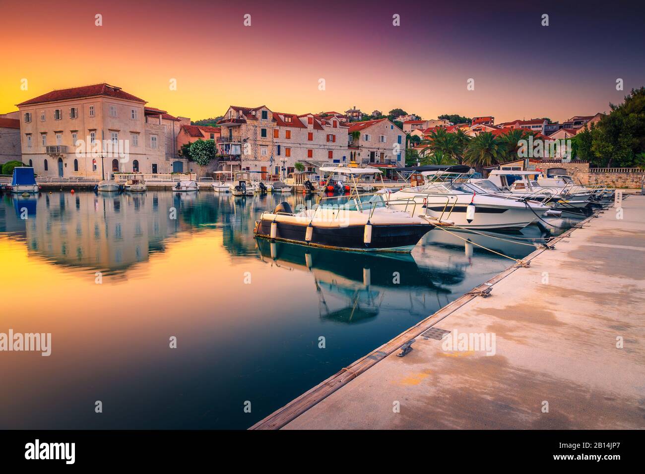 Boote und Motorboote im Hafen im Morgengrauen. Schöne Morgenlichter bei Sonnenaufgang und spektakuläre Promenade im Hafen, Trogir, Dalmatien, Croa Stockfoto
