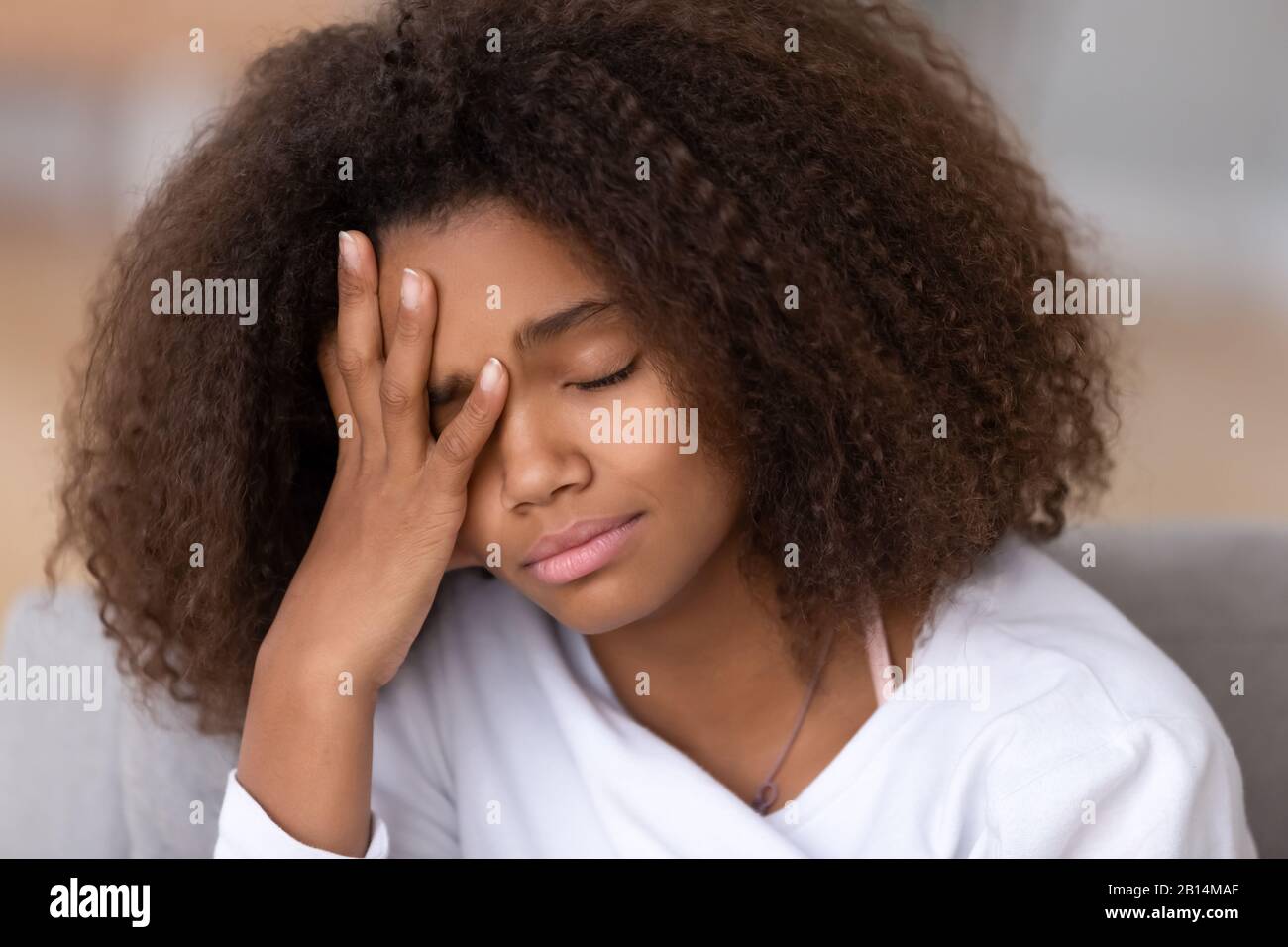 Trauriges oder gelangweiltes afroamerikanisches Teenager-Mädchen, das Kopfschmerzen hat, schläfrig Stockfoto