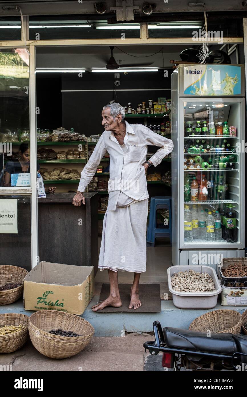 Und alter Mann, der in einer Ladeneröffnung in Indien steht. Stockfoto