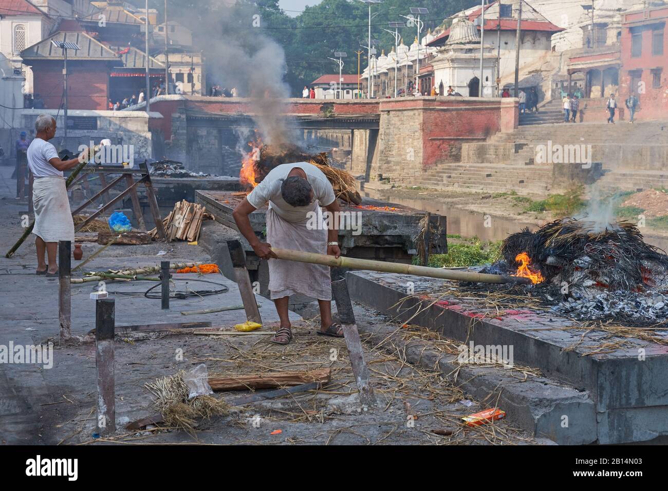 Im Paschupatinath-Tempel. Kathmandu, Nepal, Männer der "unantastbaren" Dom-Kaste, die traditionell in Hindu-Kremationen eingesetzt werden, stocken Beerdigungspyren Stockfoto