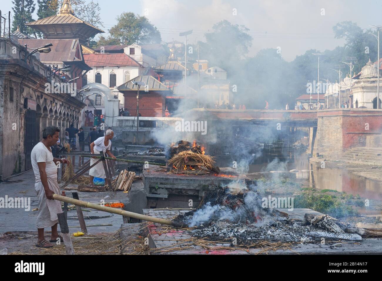 Im Paschupatinath-Tempel. Kathmandu, Nepal, Männer der "unantastbaren" Dom-Kaste, die traditionell in Hindu-Kremationen eingesetzt werden, stocken Beerdigungspyren Stockfoto
