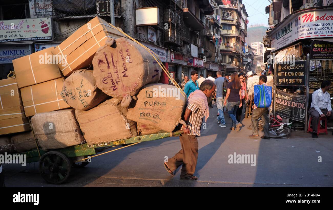 Ein Handwagen Puller im Geschäftsgebiet Kalbadevi Road, Bhuleshwar, Mumbai (Bombay), Indien, zieht eine enorme Last auf seinen Trolley Stockfoto