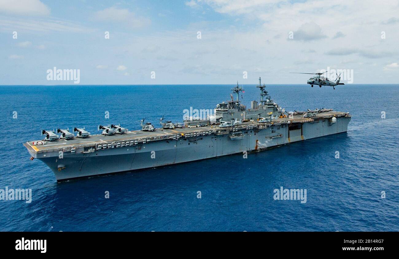Ein U.S. Navy MH-60S Sea Hawk Hubschrauber, Hubschrauber Meer Combat Squadron (HSC) 25 fliegt neben den Amphibisches Schiff USS Wasp (LHD 1) im philippinischen Meer März 20, 2018. Die Wespe, Teil der Wasp Expeditionary Strike Group, mit Eingeschifft 31 Marine Expeditionary Unit (31 MEU), ist die in der indopazifischen Region Bedienbarkeit mit Partnern zu verbessern, dienen als ready-Response Force für jede Art von Kontingenz und der Up-Gunned ESG Konzept voraus. (U.S. Marine Foto von Mass Communication Specialist 3. Klasse Taylor König) Stockfoto