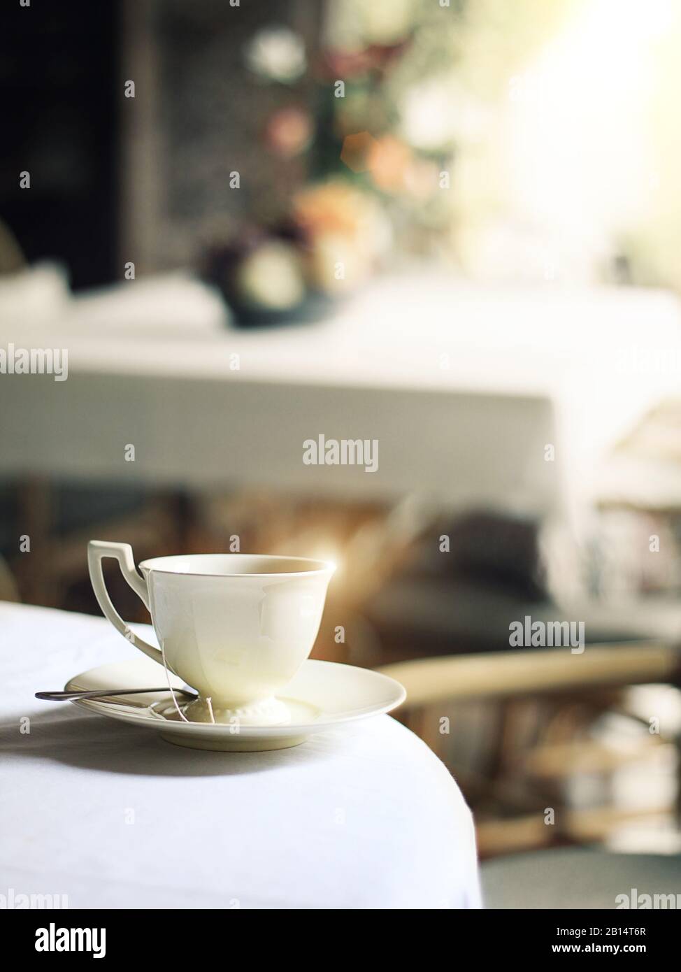 Tasse heißen Dampfkaffees auf dem Tisch im Café mit morgendlicher glitzernden Lichtem Stockfoto