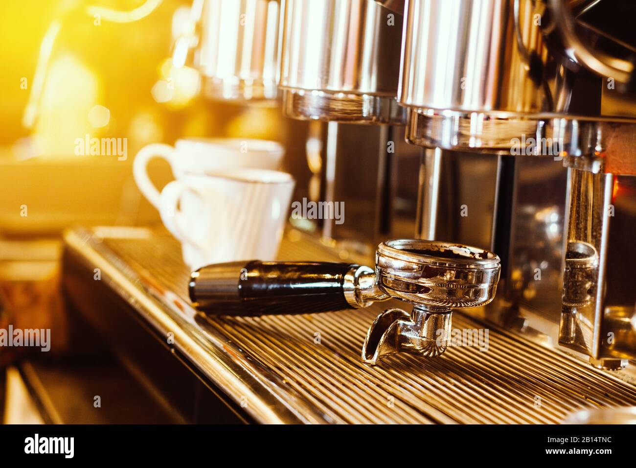 Kaffeemaschine. Kaffeemaschine, die frischen Kaffee in weiße Kaffeetassen im Restaurant, in der Bar oder im Café zubereitet. Warmes Licht Stockfoto