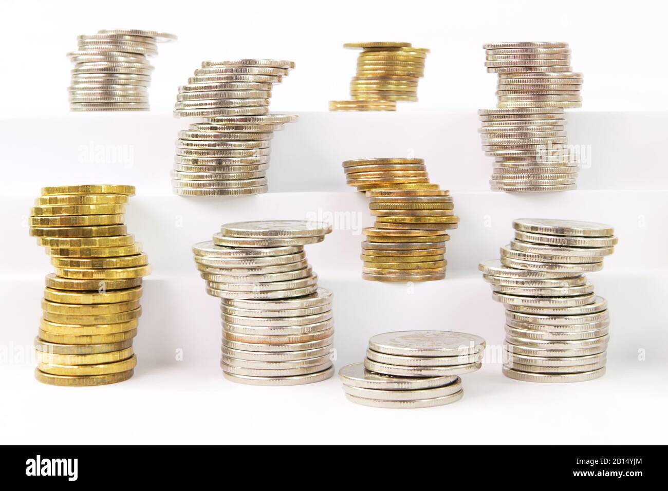 Volatilität der Währung während einer Krise. Säulen verschiedener instabiler Metallmünzen auf weißen Stufen Stockfoto