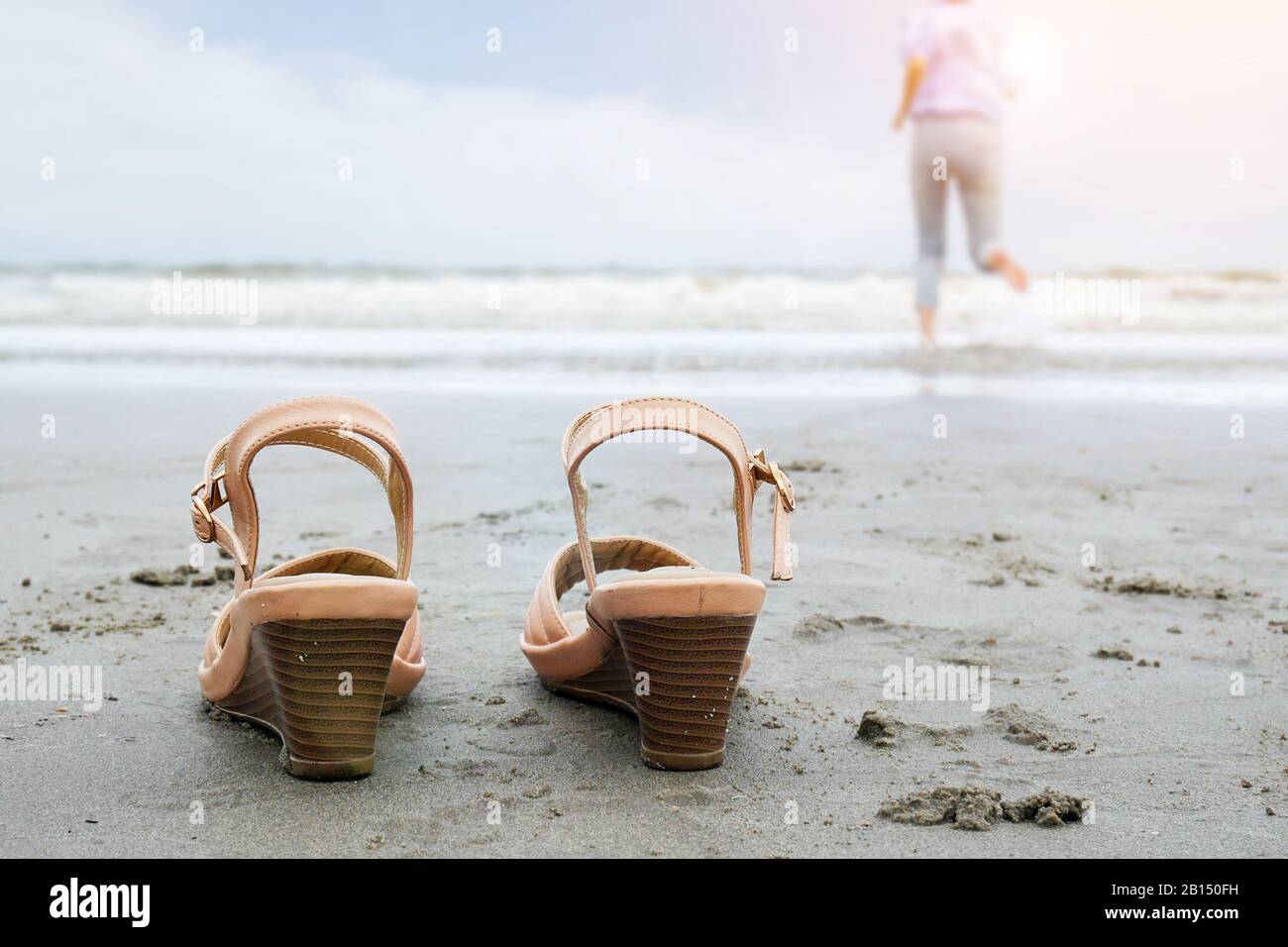 Urlaub am Strand Urlaub Lifestyle-Konzept - Glückliche Geschäftsfrau mittleren Alters nimmt Schuhlauf ins Meer mit Barfuß genießen schöne sei Stockfoto
