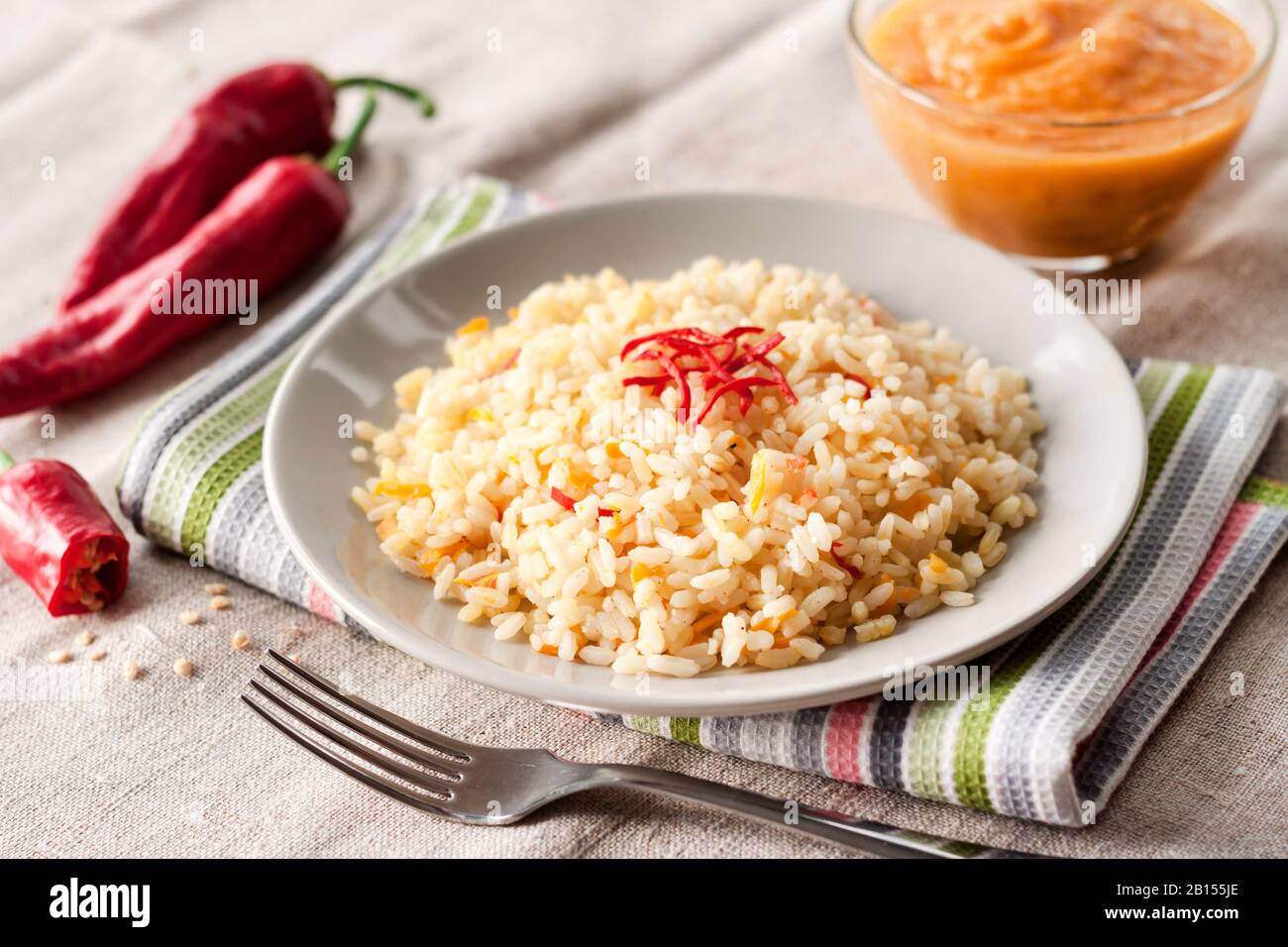 Würziger, parochoter Reis mit Karotten, gelbem Zucchini und Chili Paprika auf einer grauen Platte Stockfoto