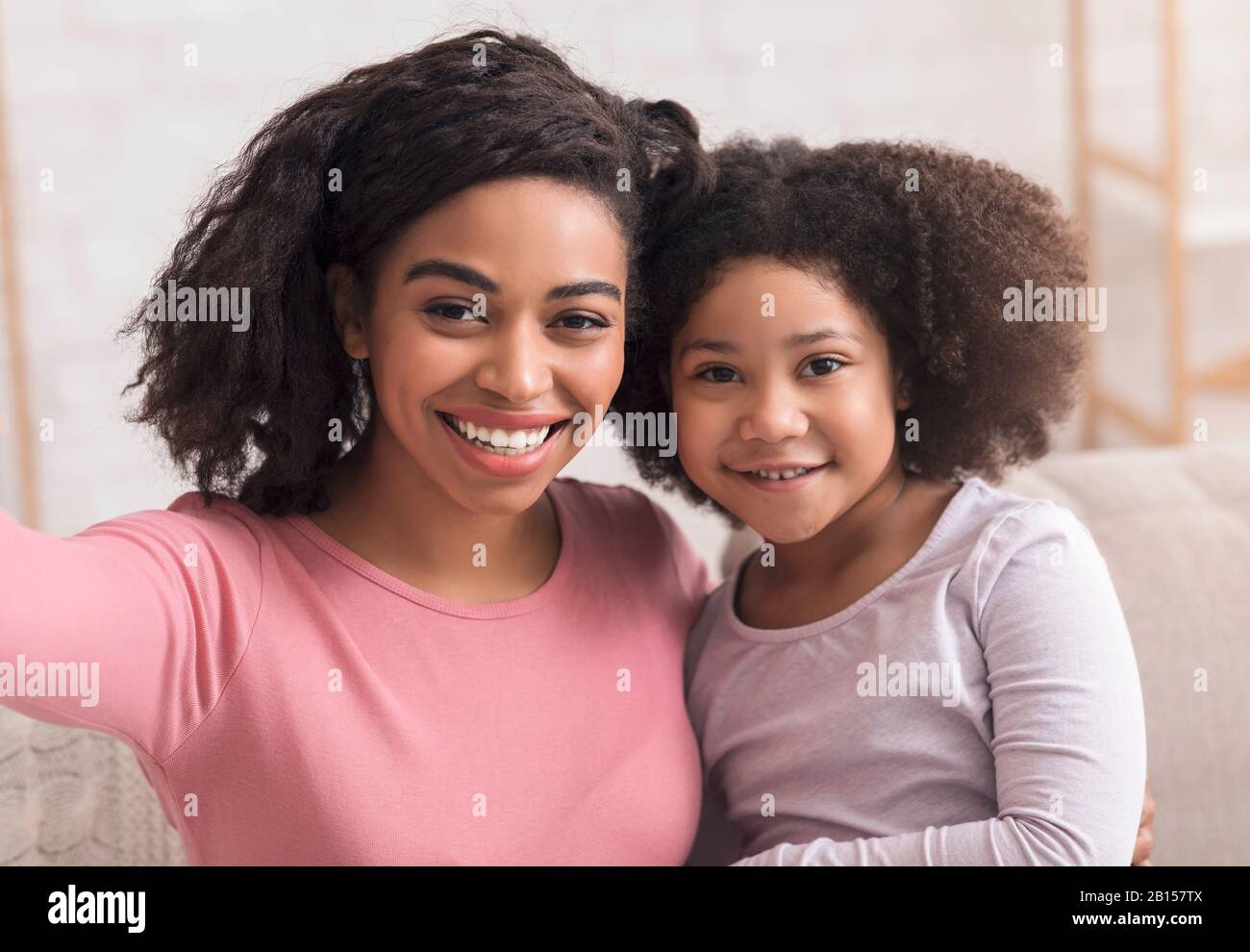 Junge Afro Mutter und ihre niedliche kleine Tochter nehmen selfie zusammen Stockfoto