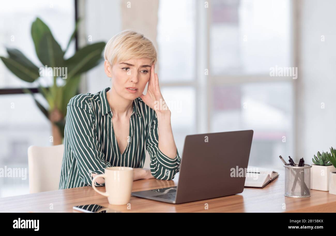 Traurige Frau Mit Blick Auf Laptop Im Modernen Büro Stockfoto
