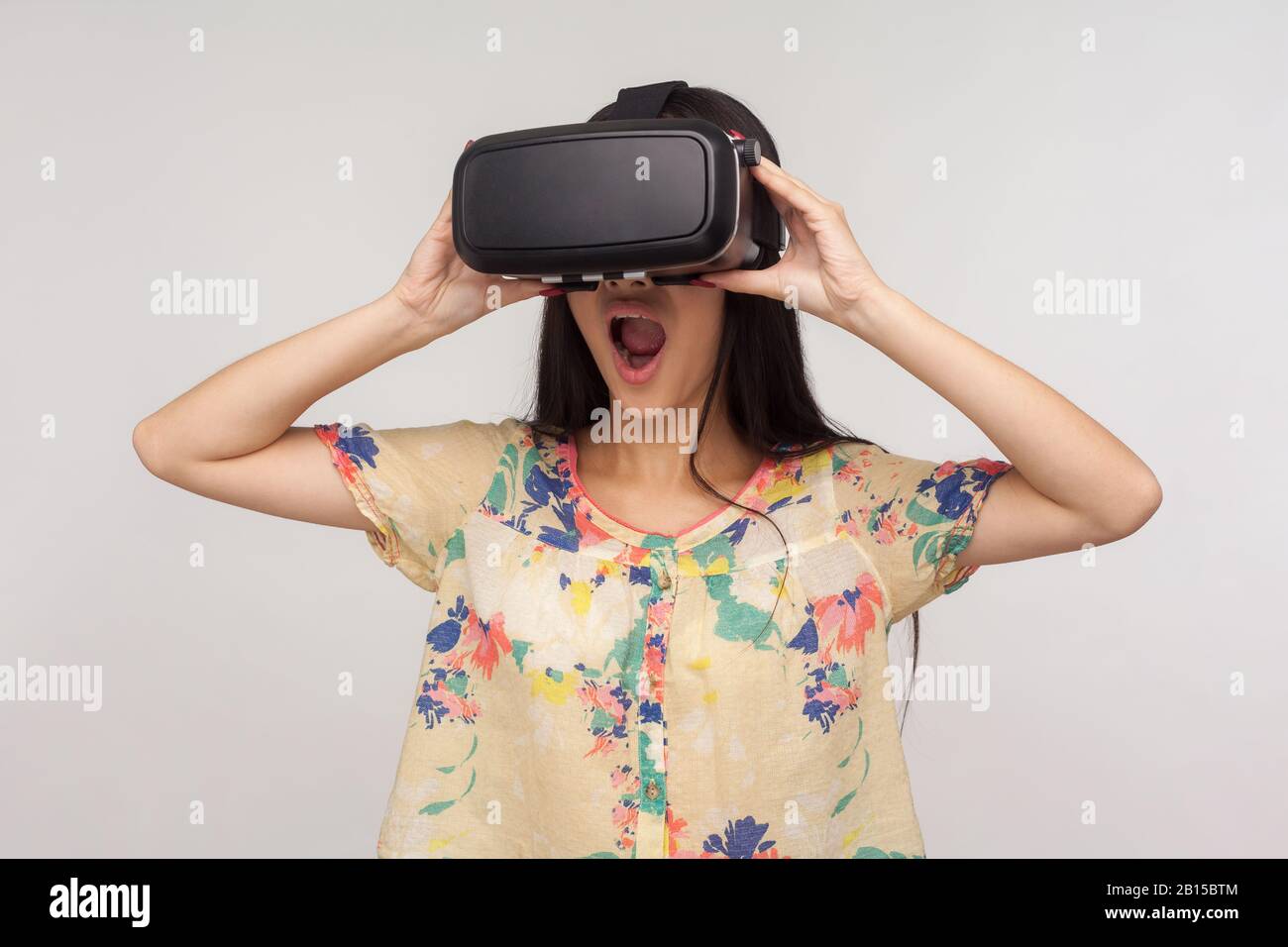 Überraschte Frau, die VR-Brille trägt und die virtuelle Welt mit erstauntem schockierten Ausdruck beobachtet, Videospiele spielt und starke Emotionen erlebt, während sie u. a Stockfoto