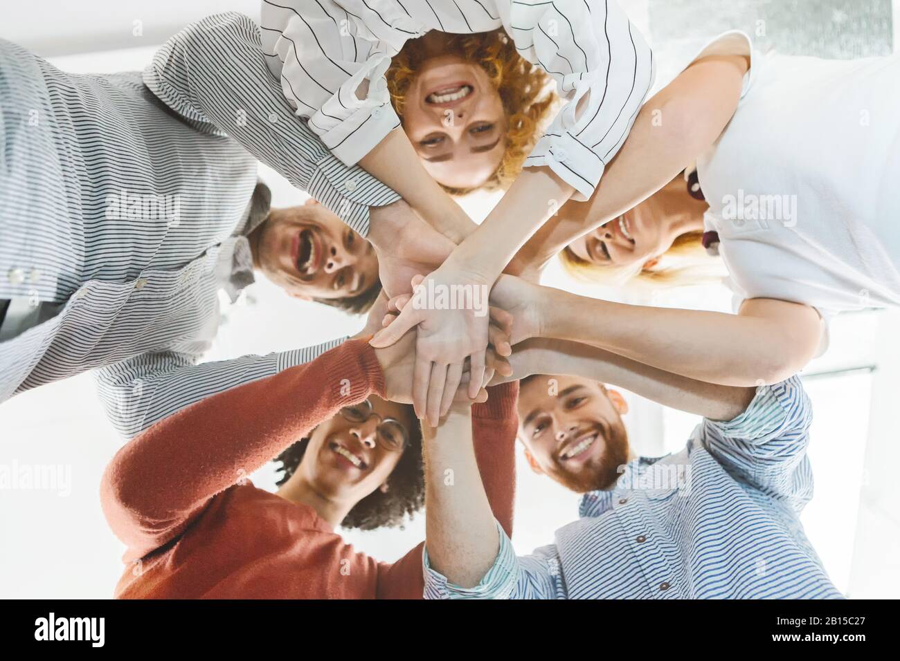 Tausendjährige multiethnische Mannschaft, die Hände zusammenbringt, unten niedrig Stockfoto