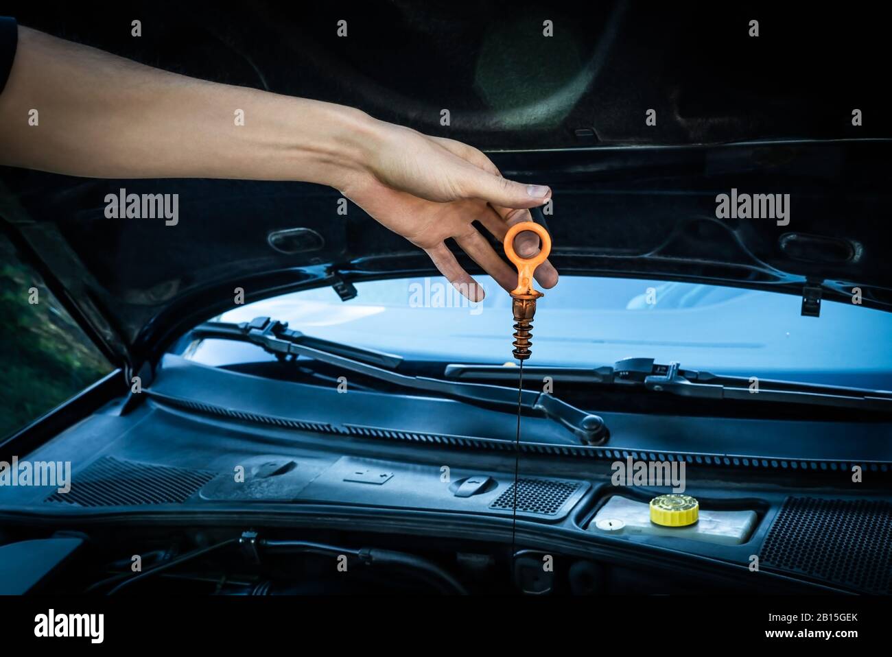 Weißer kaukasischer Stecker schmutziger Tischler Hand mit fettigem Kunststoff-Messstab prüfen des Ölstands des synthetischen Motors für die Wartung des Motors. Stockfoto