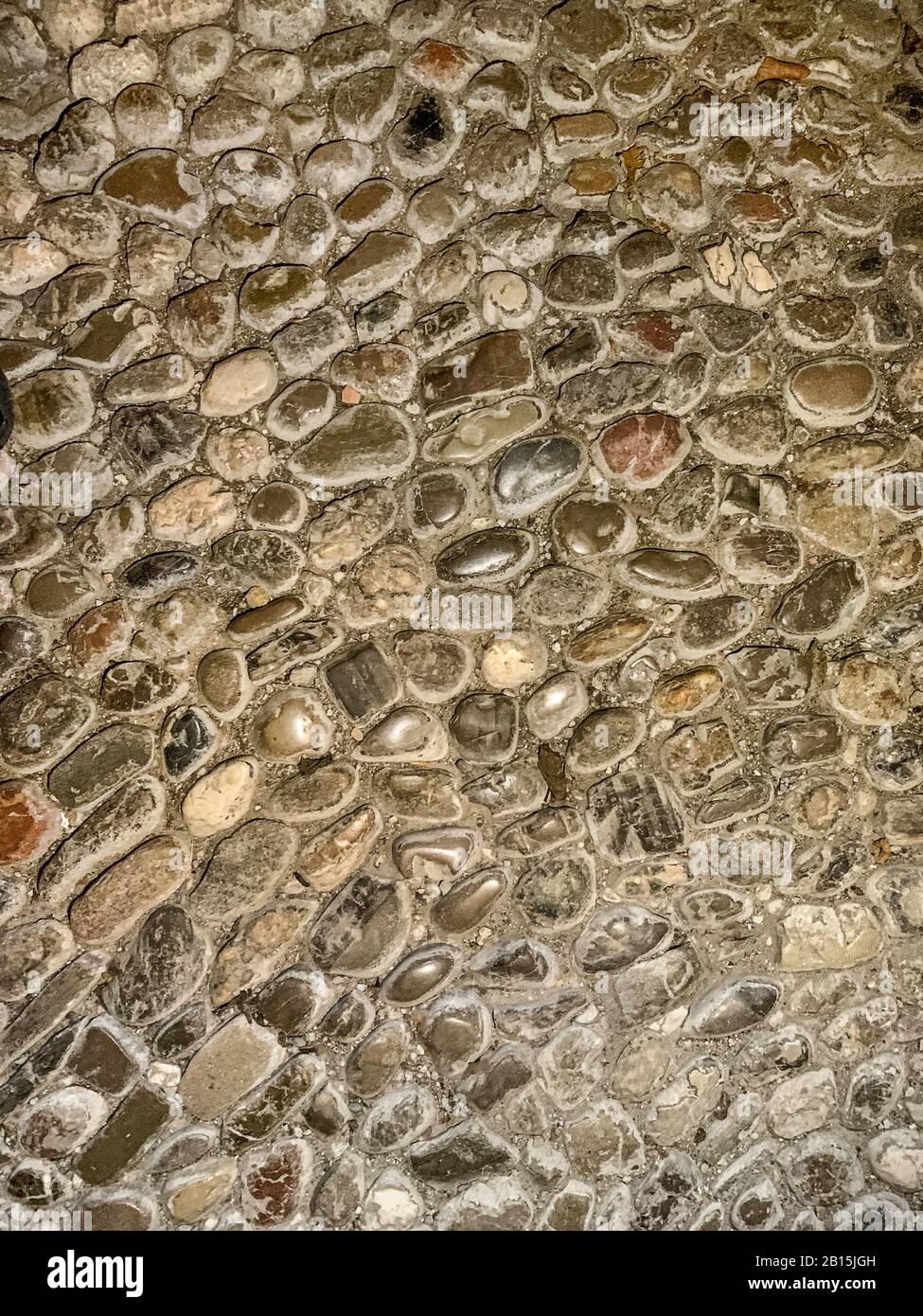 Boden aus Kieselsteinen des Flusses. Alte, verwitterte und zupfte Kopfsteinpflaster, aus runden Flusssteinen unterschiedlicher Größe, verfugt mit Mörtel. Nahaufnahme. Stockfoto