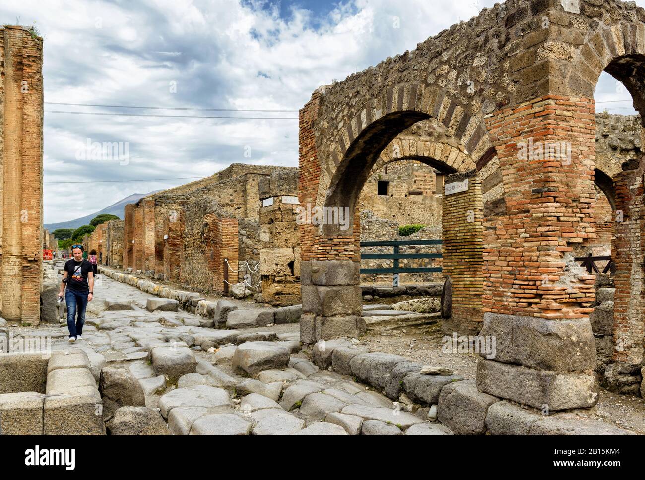 Pompeji, ITALIEN - 13. MAI 2014: Touristenspaziergänge in der Straße unter den Ruinen. Pompeji ist eine alte römische Stadt, die durch den Ausbruch des Vesuviu gestorben ist Stockfoto