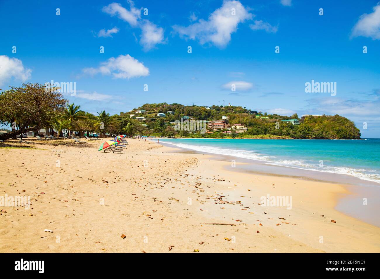 Bezaubernder Sandstrand an einem hellen sonnigen Tag mit azurblauem Himmel. Ein beliebter Urlaubsstrand mit Kreuzfahrtschiffen-Touristen Stockfoto