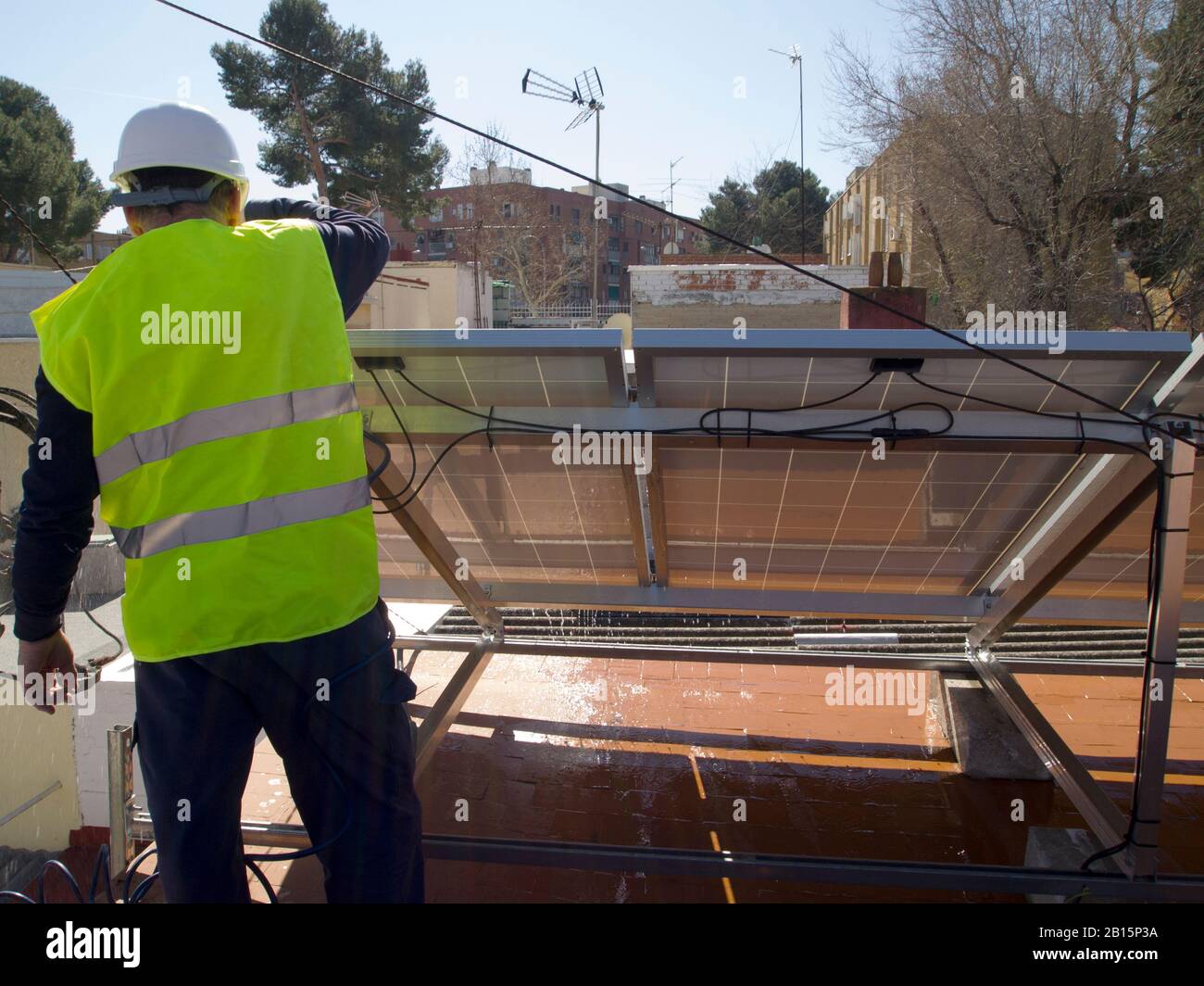 Kaukasischer erfahrener Techniker, der die Solarpaneele repariert und gereinigt. Alternative Stromquelle, nachhaltige Ressourcenkonzeption. Stockfoto