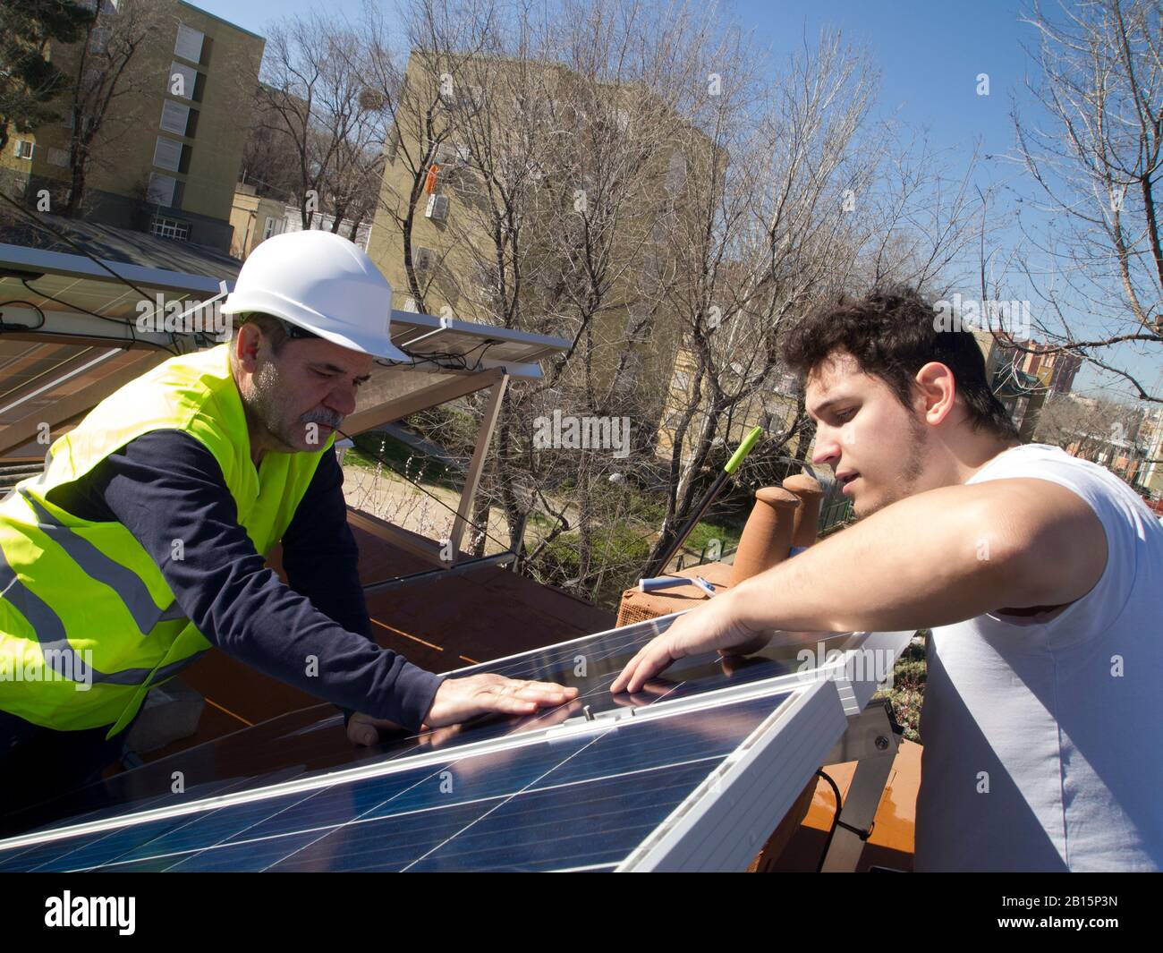 Kaukasischer erfahrener Techniker, der die Solarpaneele seinem jungen Kunden zeigt. Alternative Stromquelle, nachhaltige Ressourcenkonzeption. Stockfoto
